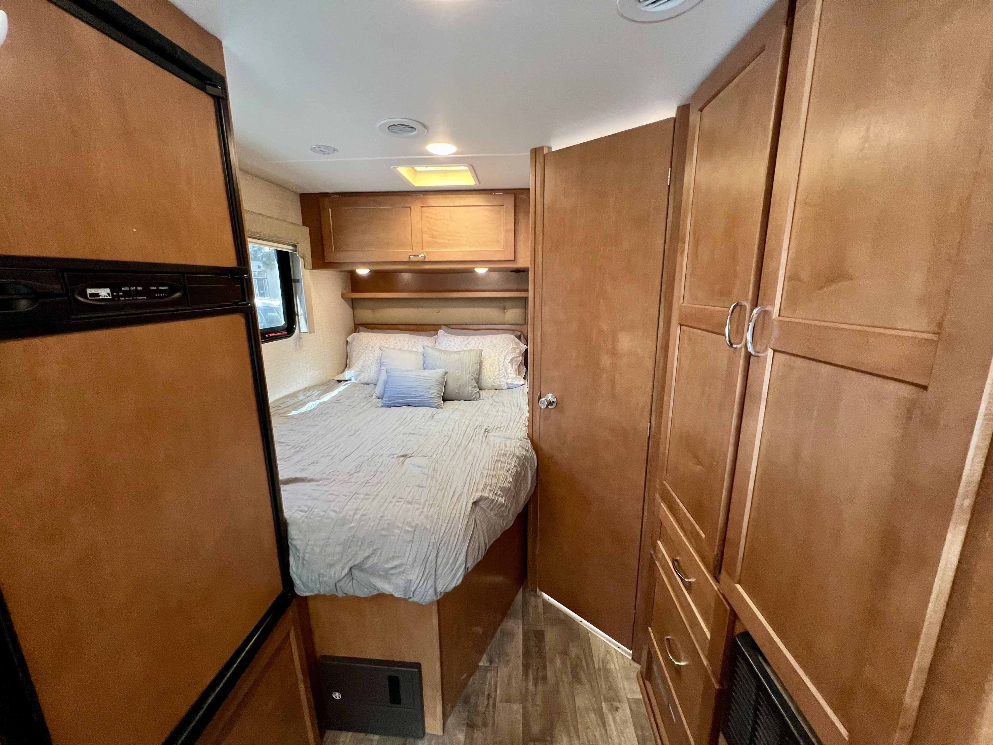 Inside this RV rental: a compact bedroom with a comfortable bed, storage, and small fridge.. Winnebago Minnie Winnie 2017