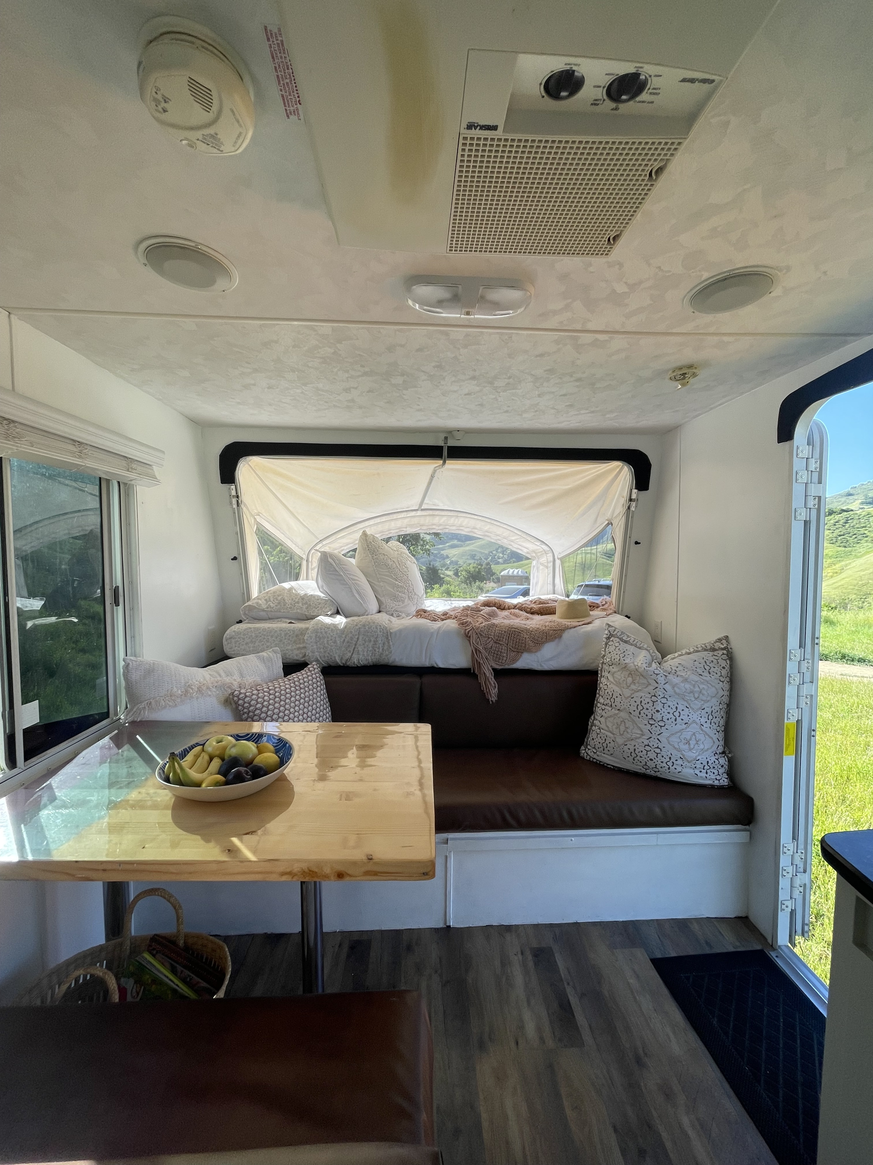 Spacious and comfortable RV rental interior with a bed, table, seating, and scenic views, ideal for a camping trip.. Forest River Wildwood 2011