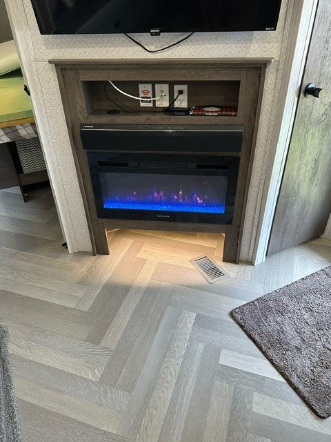 RV rental's modern interior featuring a smart TV, electric fireplace with blue flames, and light herringbone floor.. Forest River Salem 2022