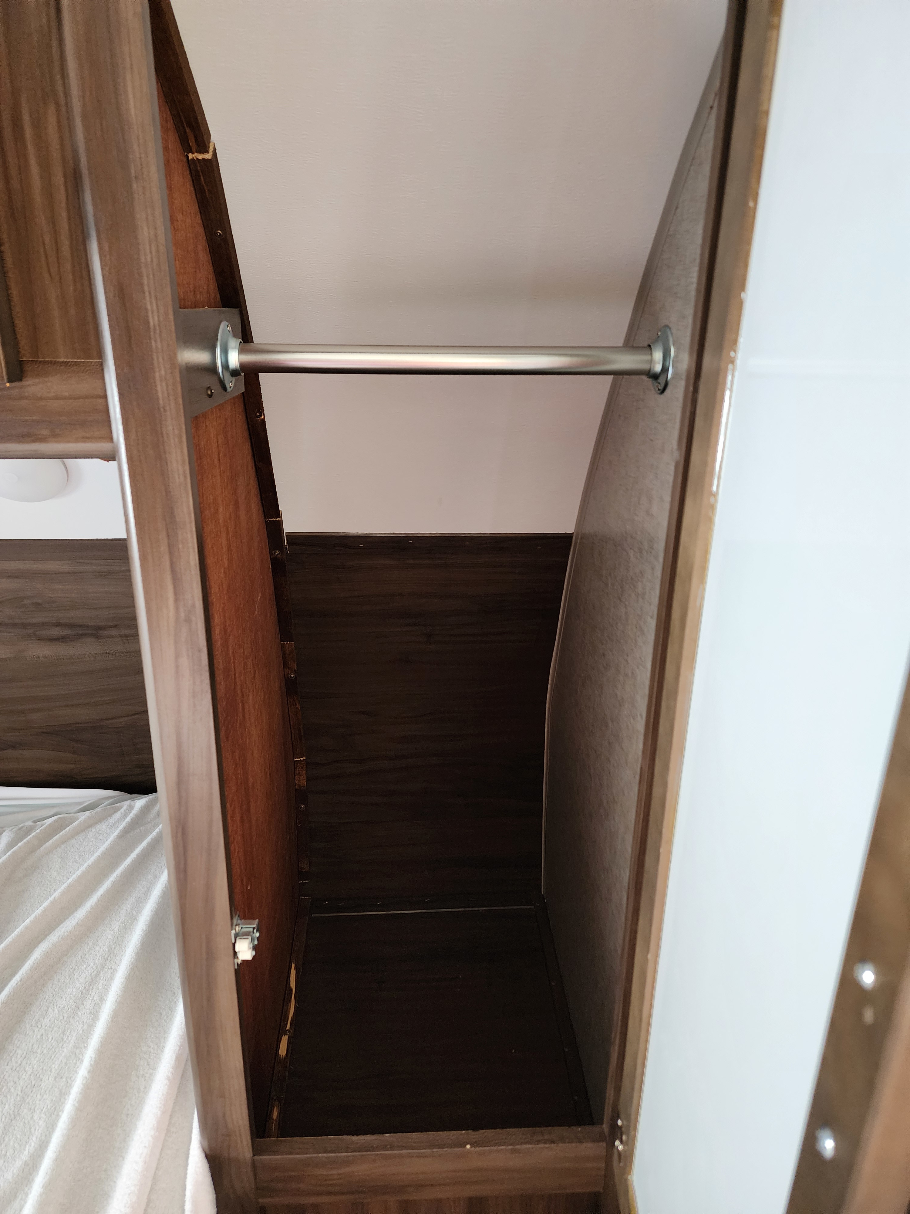 This is an RV rental's compact wardrobe, featuring a sturdy hanging rod for clothing storage within the bedroom area.. Forest River Cherokee Grey Wolf 2018