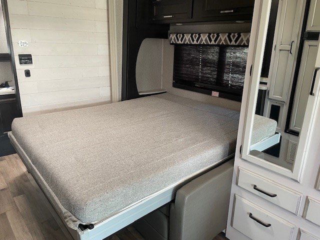 Inside an RV rental: a modern murphy bed extended, offering a cozy sleeping area within the compact living space.. Entegra Coach Odyssey 2021
