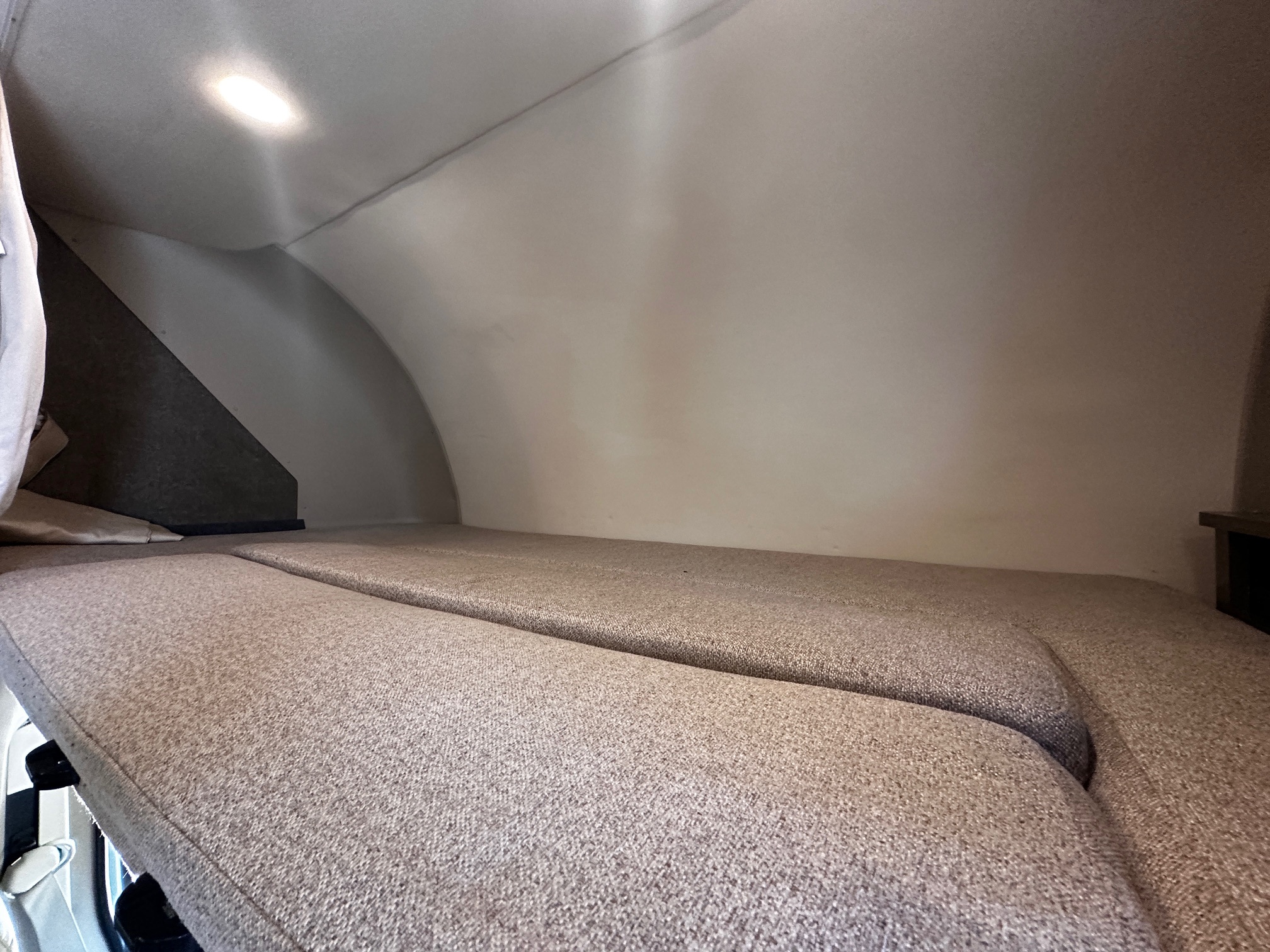 Cozy RV rental bed setup, featuring two upholstered cushions and an overhead light, perfect for travelers.. Holiday Rambler Augusta 2019