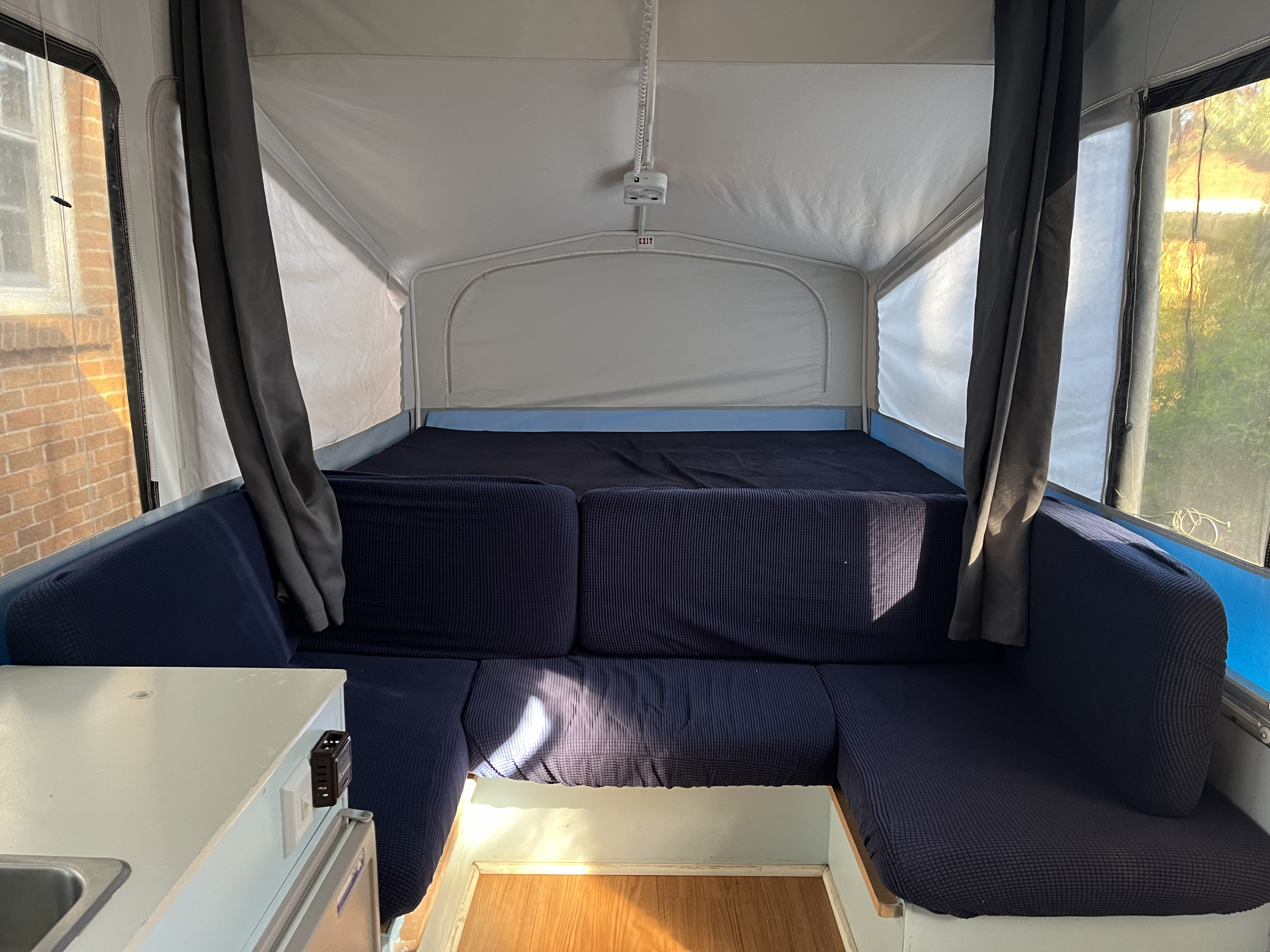 RV rental interior: blue upholstered seating, a bed, and bright windows, offering a cozy and functional space.. Jayco Jay 2007