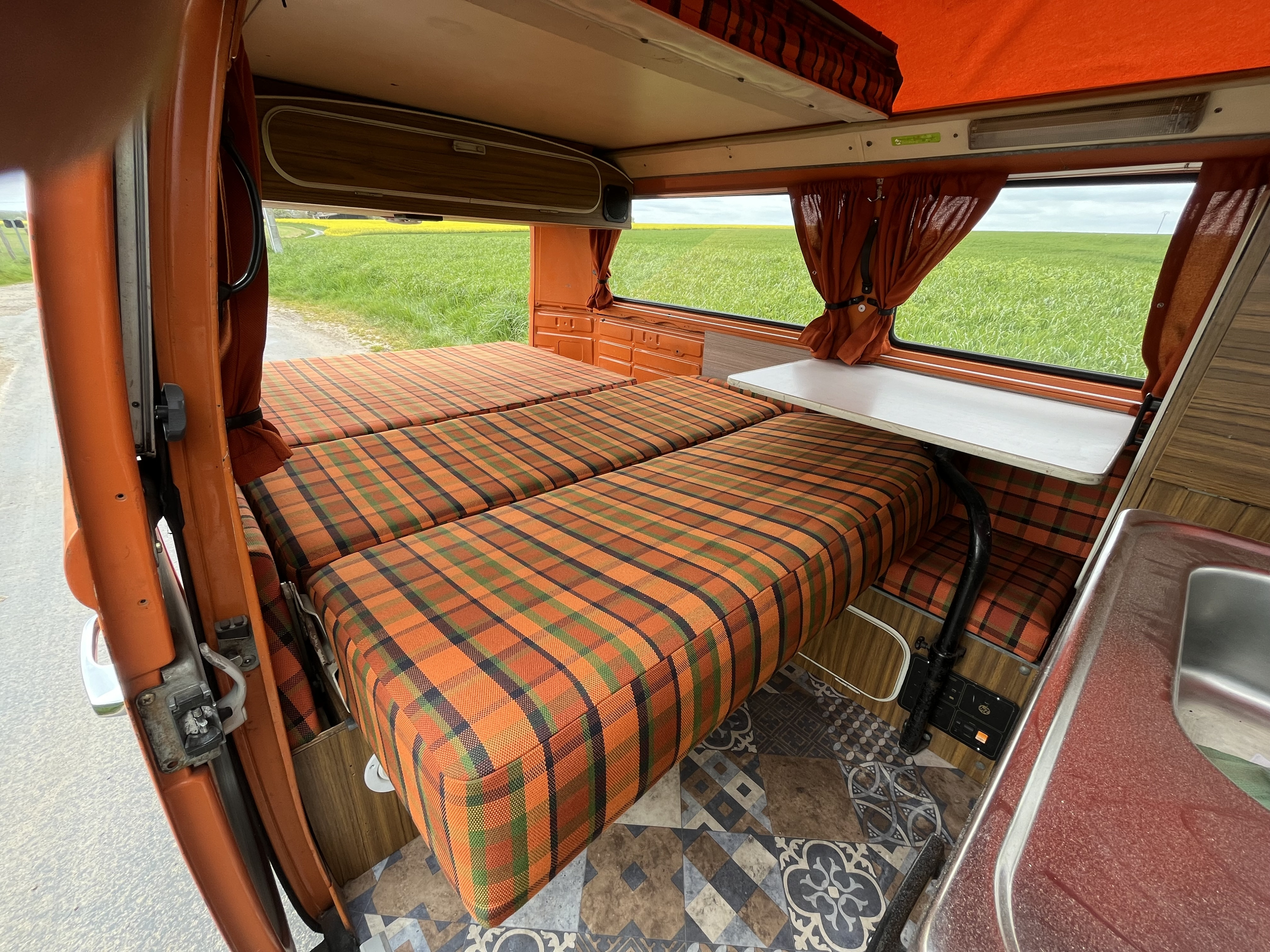 Step inside this cozy vintage camper RV rental with plaid beds, a table, and scenic views. Perfect for travel!. Volkswagen westfalia 1978
