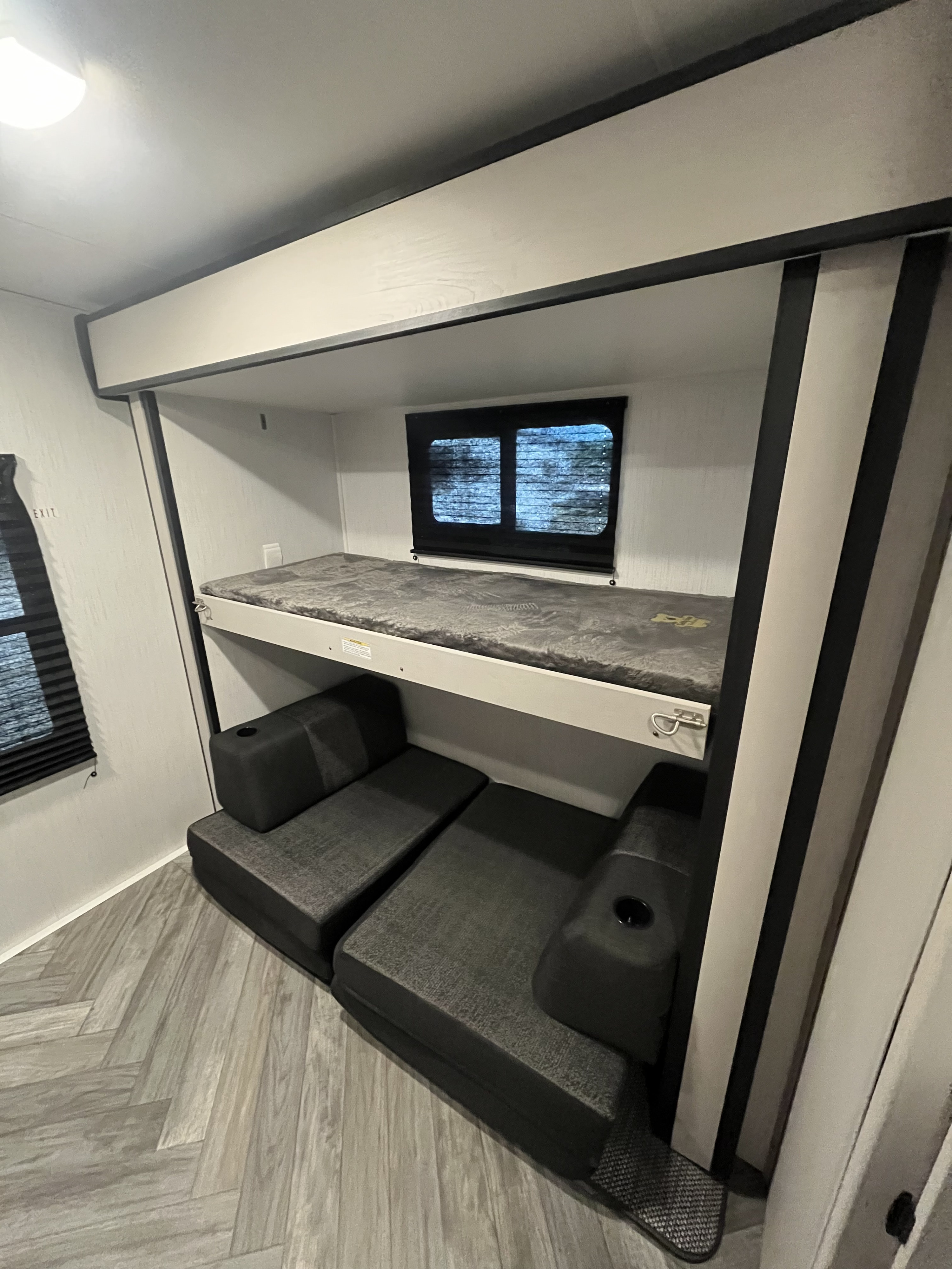 RV rental interior showcasing comfortable bunk beds with a grey mattress and a versatile seating area below, for relaxing.. Heartland Mallard 2023