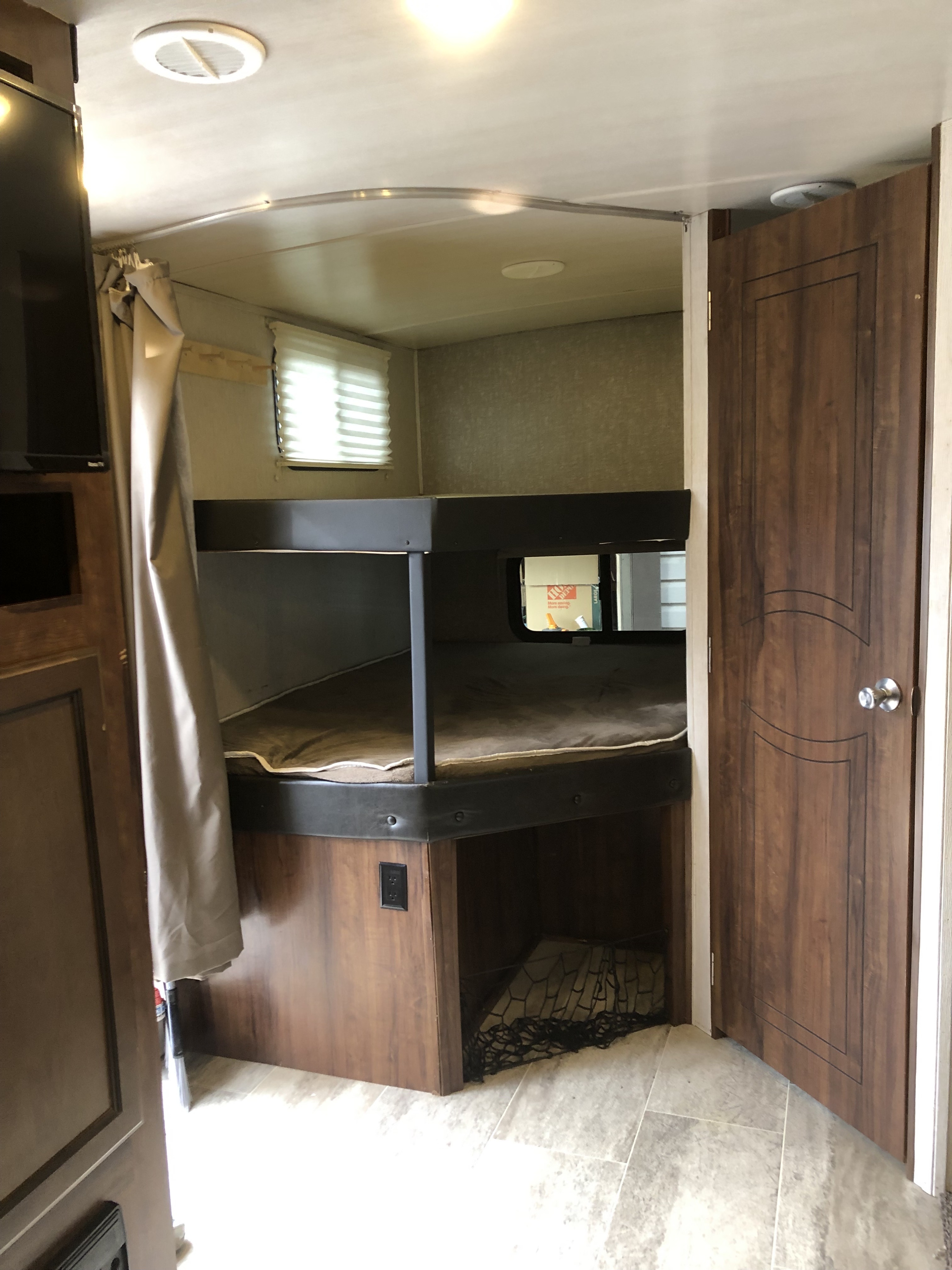 RV rental interior showcasing bunk beds, storage net, and a wooden door. Features include windows, ceiling vent, and light.. Heartland RVs Wilderness 2019