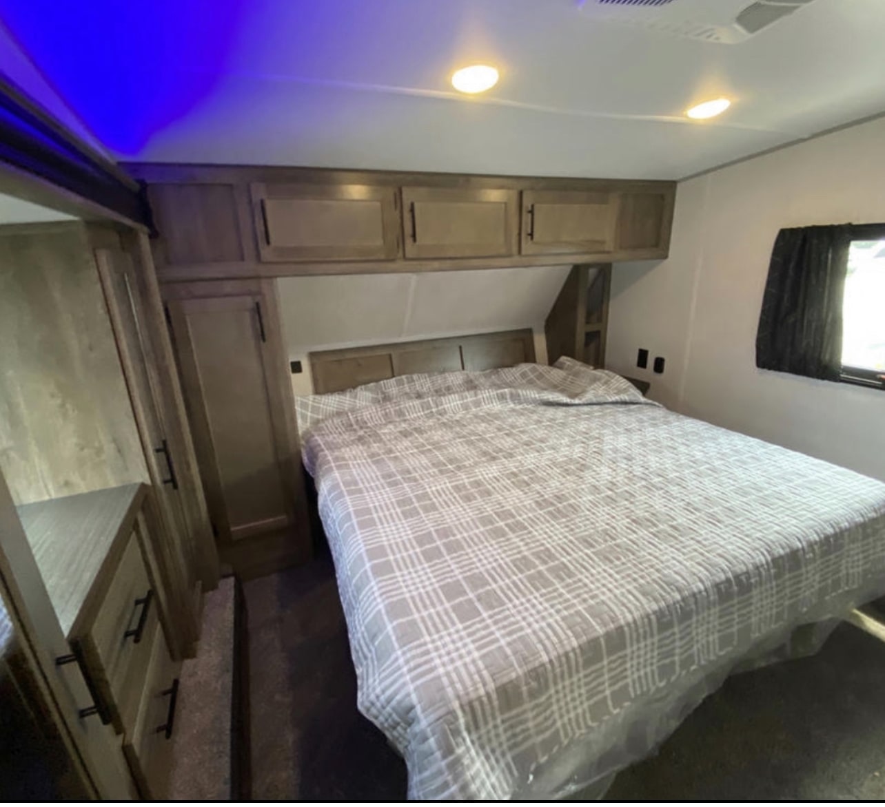 Inside an RV rental, a cozy bedroom featuring a large bed, built-in storage, and ambient lighting.. Forest River Cherokee Wolf Pack 2021