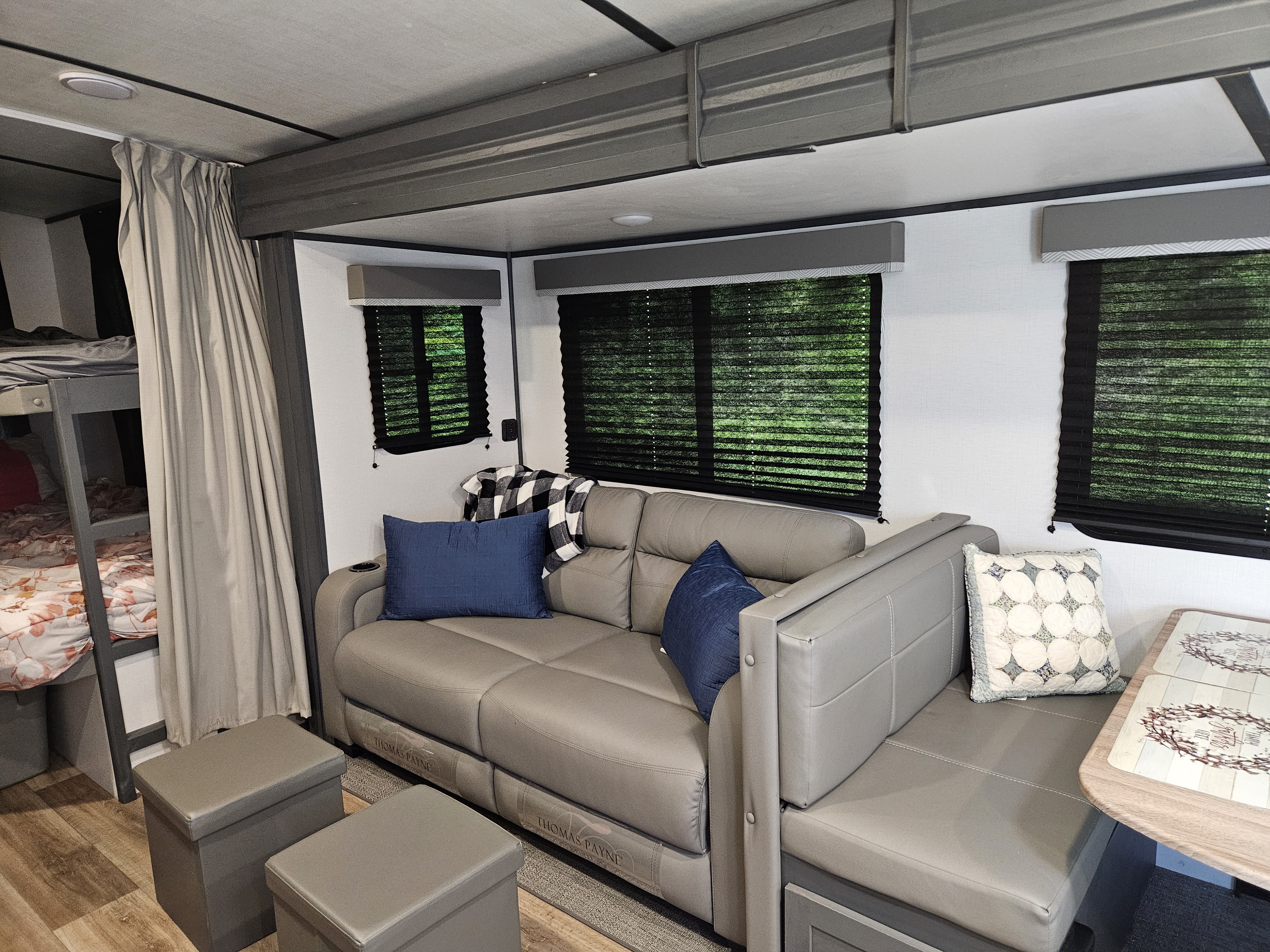 RV rental interior showing a modern living area with a grey sofa, dinette, and bunk beds.. Keystone RV Bullet Ultra Lite 2022