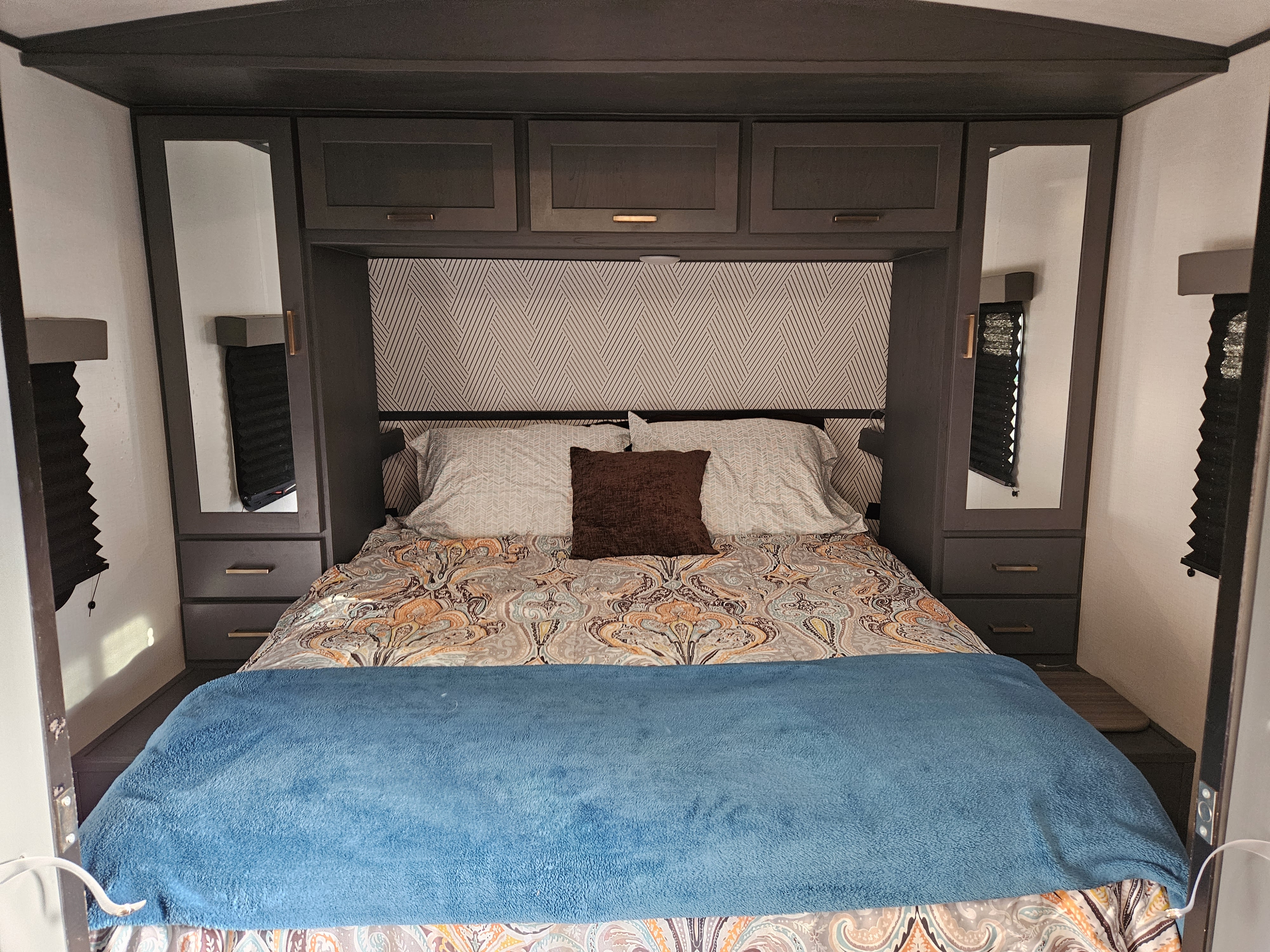 Cozy RV rental bedroom with patterned bedding & built-in storage. Ideal for travel comfort.. Keystone RV Bullet Ultra Lite 2022