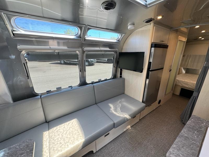 This modern rv rental interior features comfortable seating, TV, full kitchen, and a rear bed area. Your camper adventure awaits!. Airstream Flying Cloud 2023