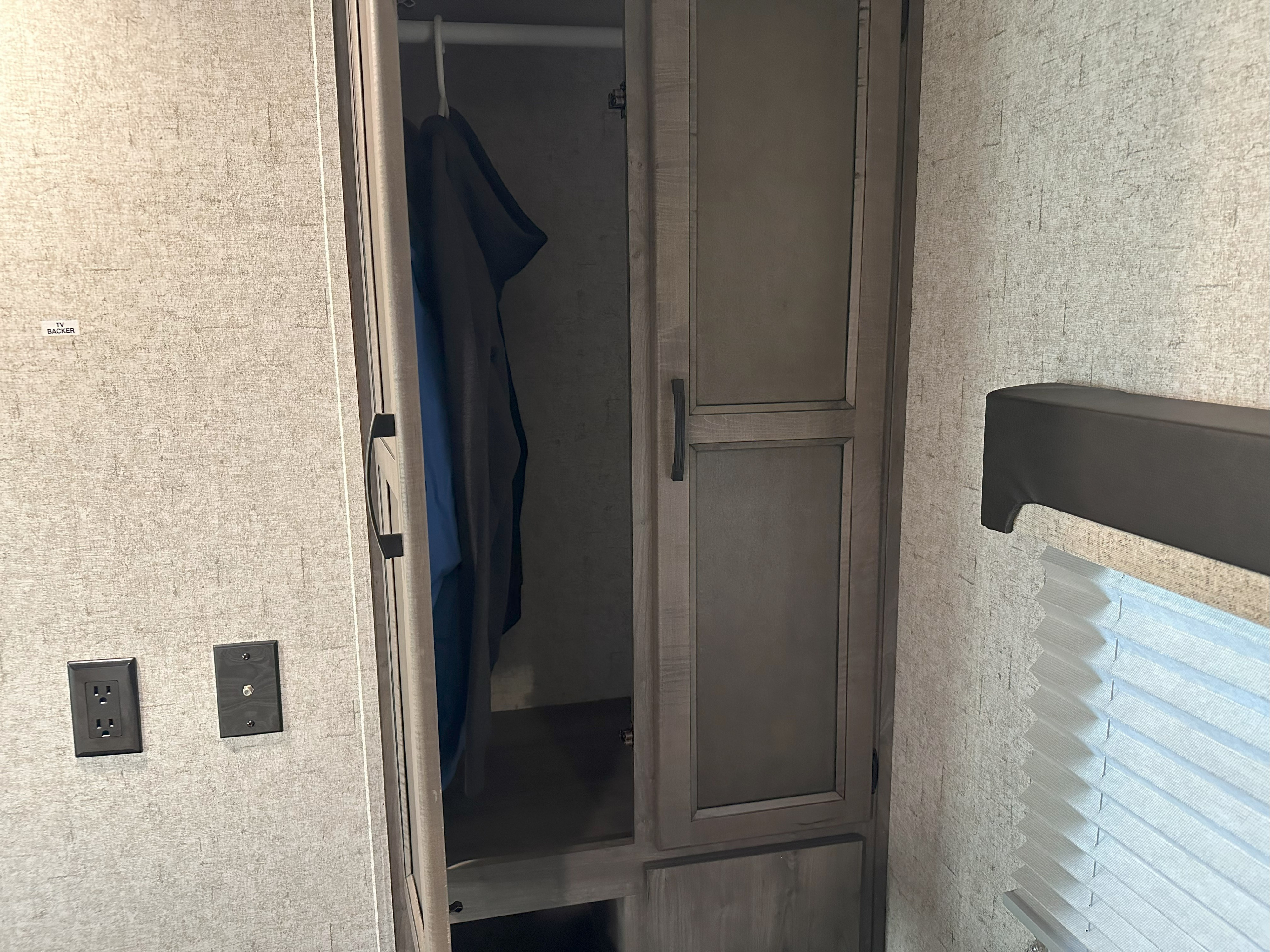 RV rental interior: A bedroom wardrobe with clothes, electrical outlet, and window blinds.. Coachmen Apex 2020