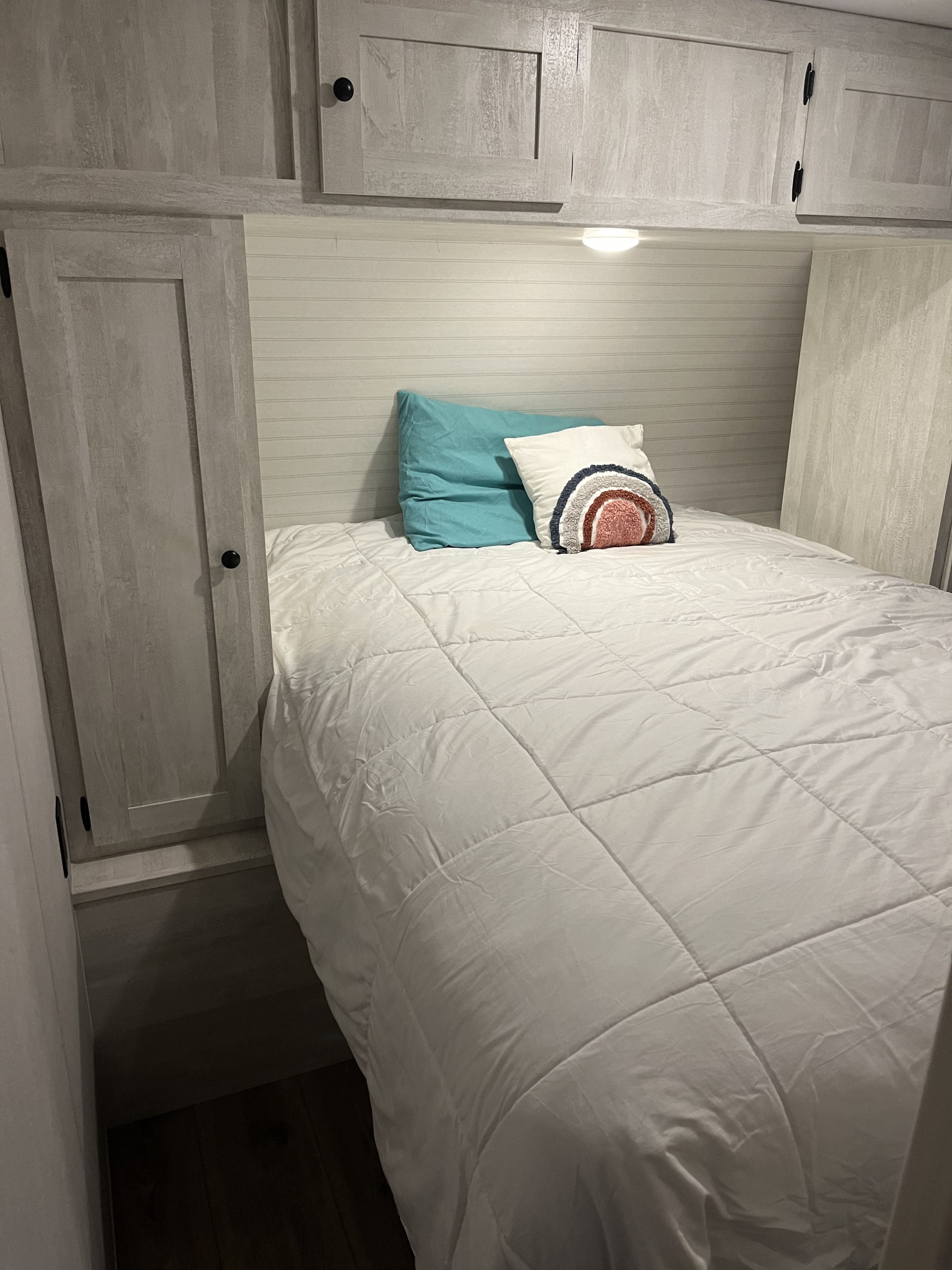 Cozy RV rental bedroom featuring overhead cabinets, side storage, and a white bed with accent pillows.. Shasta RVs I5 526DB 2024