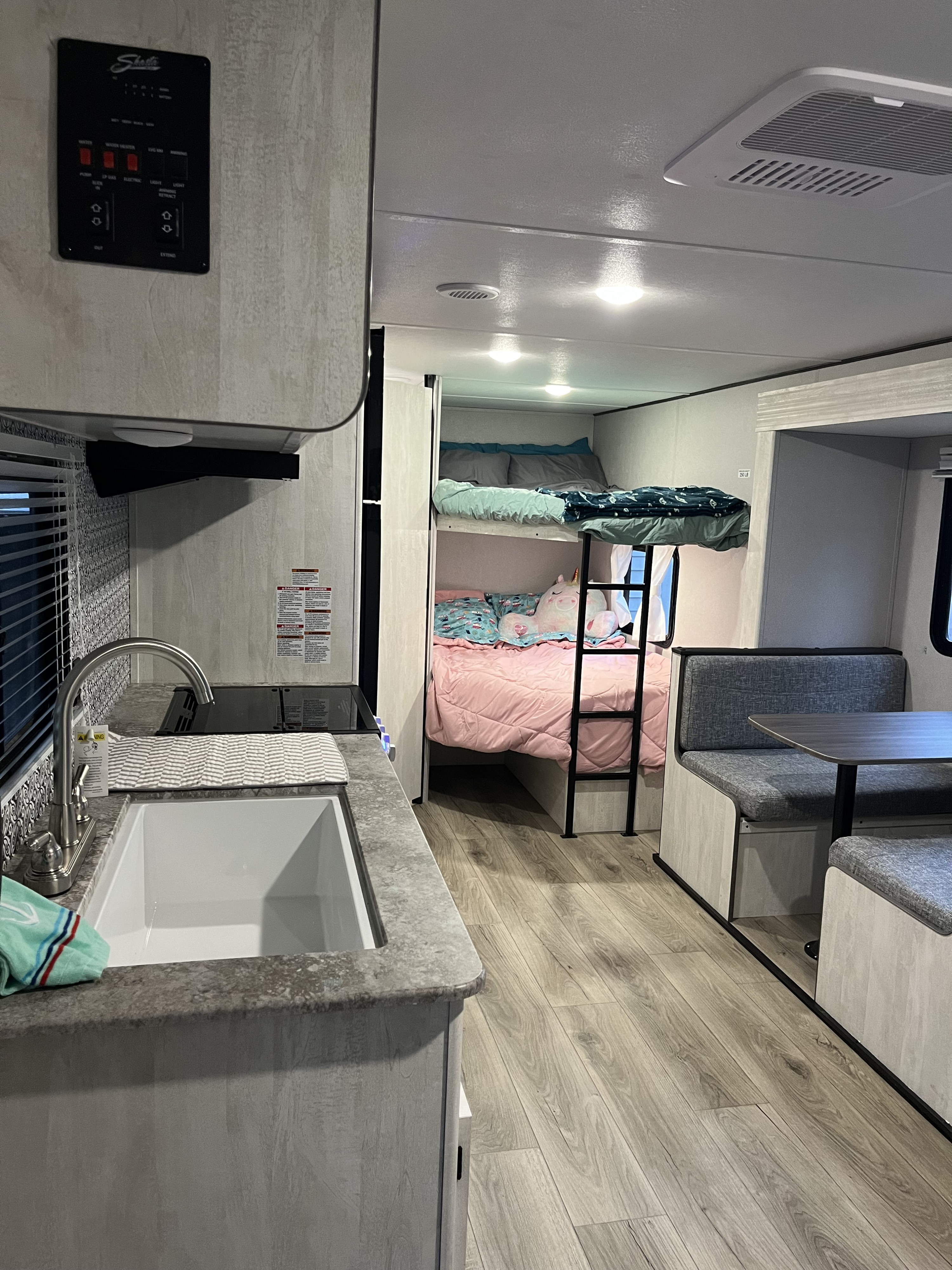 RV rental interior: kitchen with sink, cozy bunk beds with pink and blue bedding, and a dinette.. Shasta RVs I5 526DB 2024