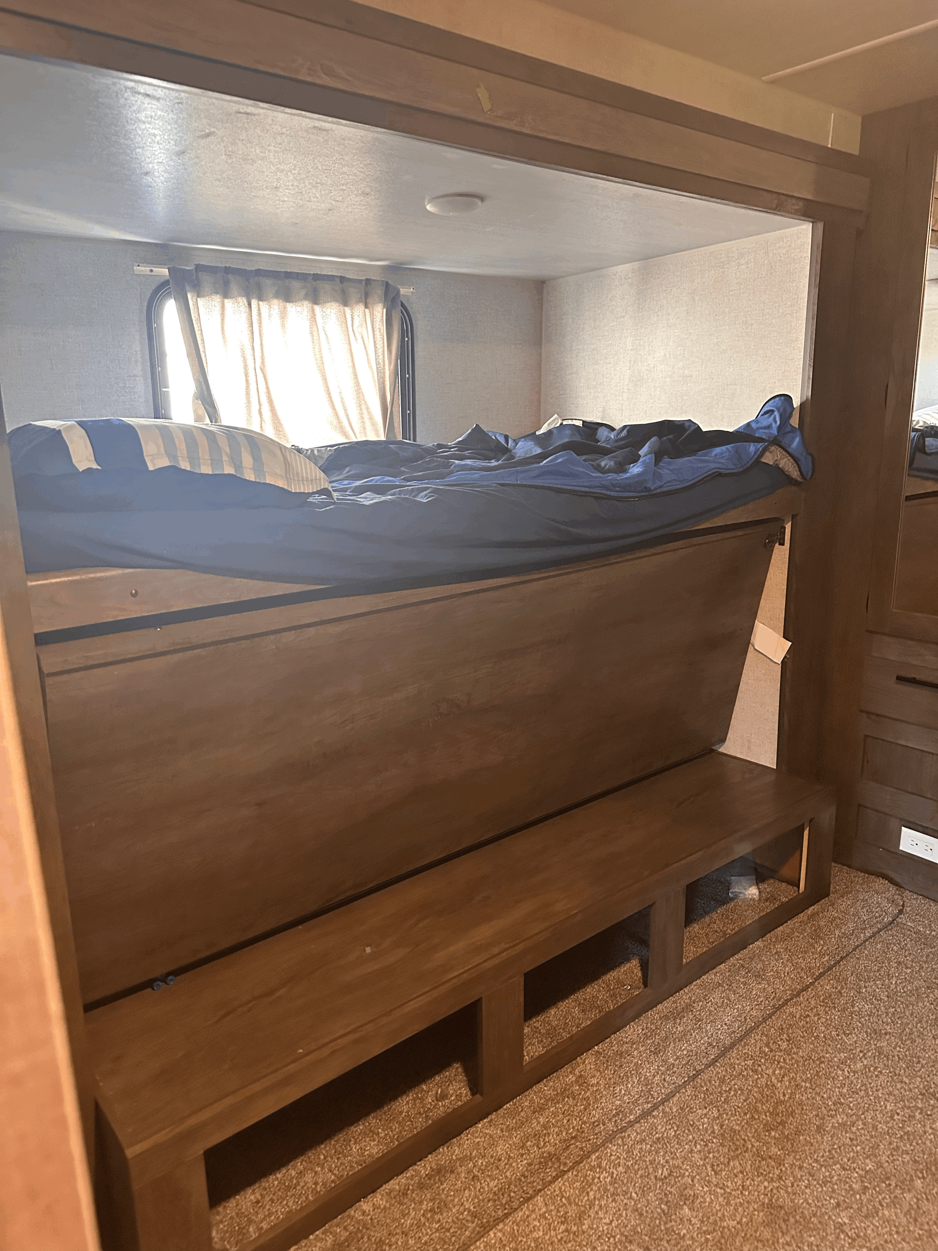 This RV rental interior features a cozy bunk bed with blue bedding, a window, and practical bench storage, all carpeted.. Forest River Salem 2020