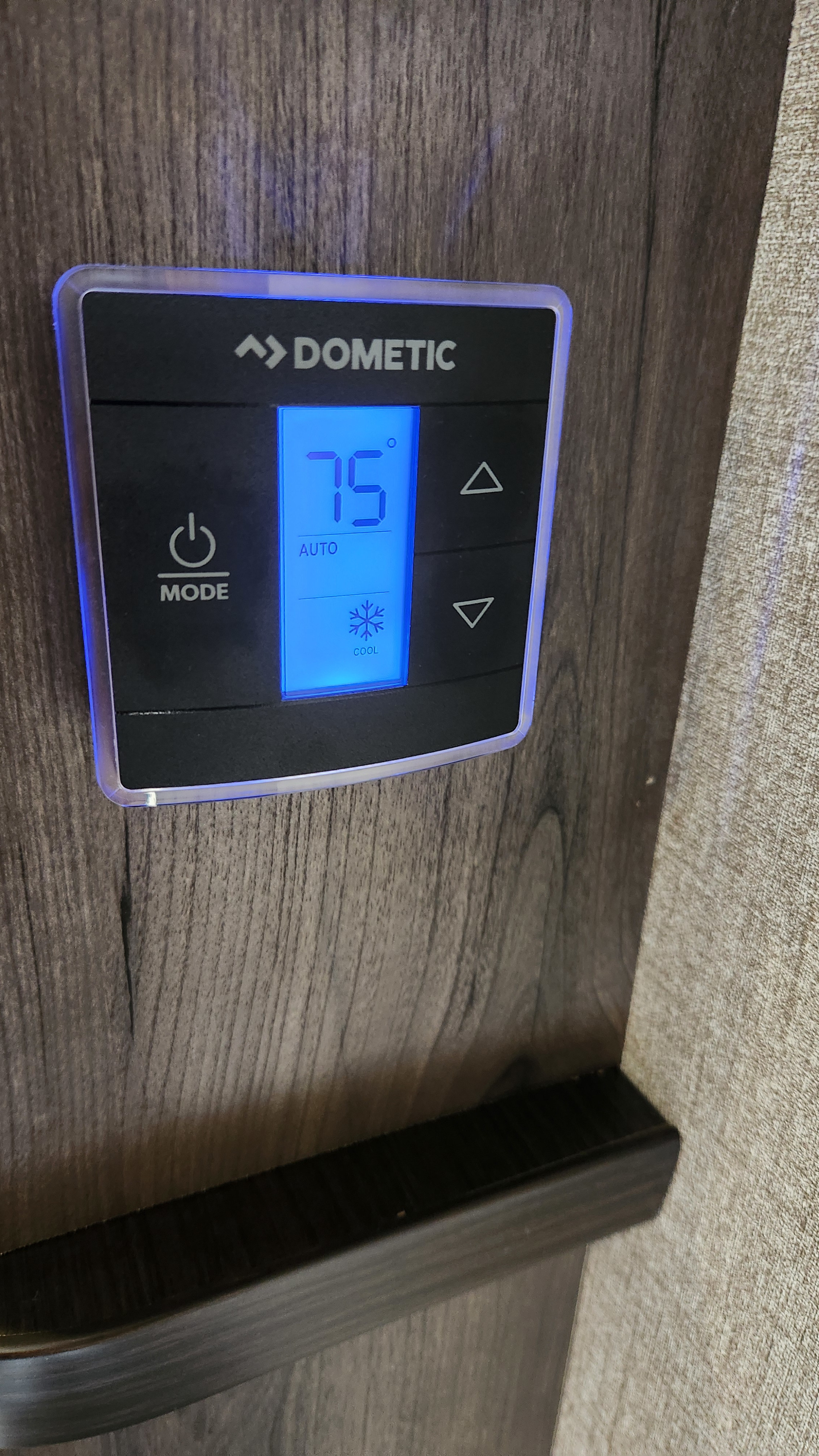 Dometic RV thermostat displaying 75°F (Cool/Auto) for an RV rental, ensuring comfortable climate control on wood paneling.. Jayco Jay Flight 2021