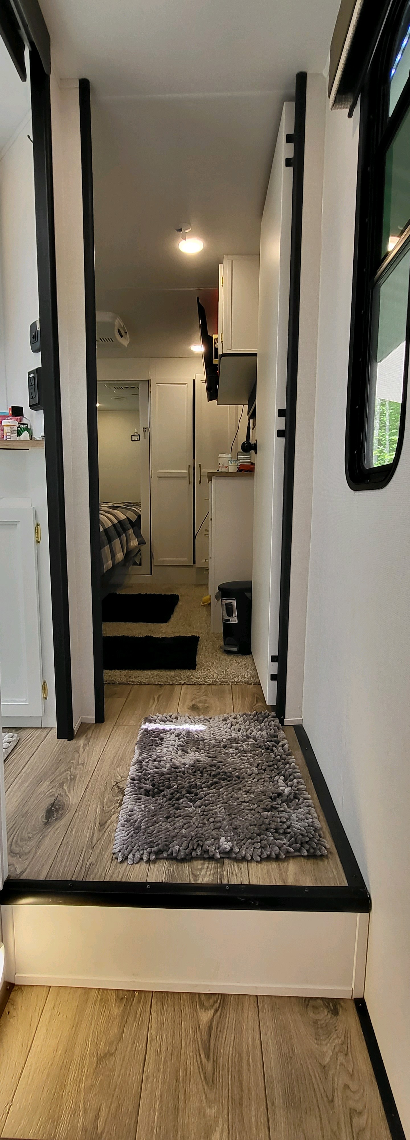 Modern RV rental interior with light wood floors, a shaggy rug, leading to a compact kitchen and cozy bedroom.. Crusader Crusader Fifth Wheel 2022