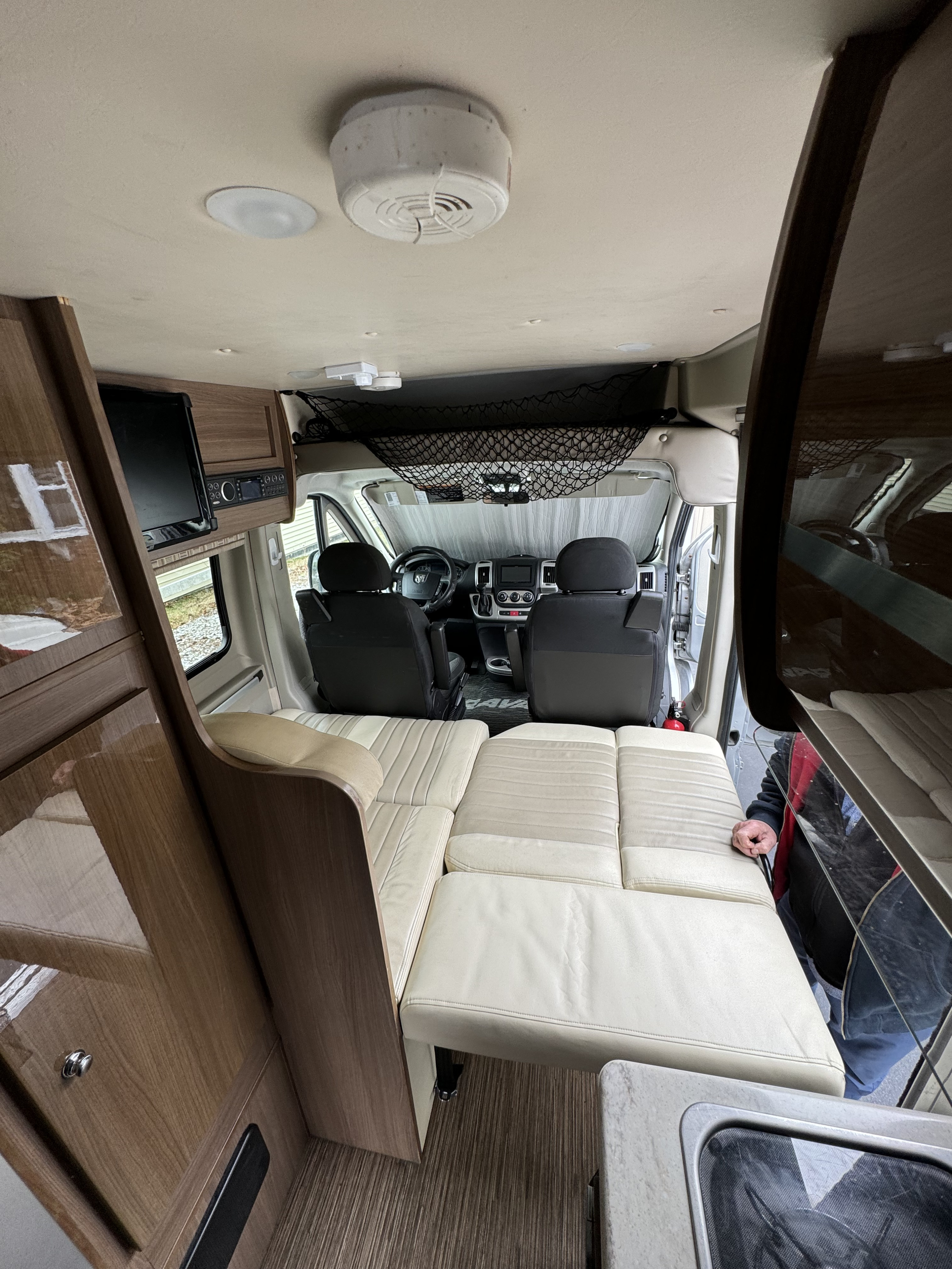 Interior of an RV rental: features convertible seating, driver's cabin, overhead storage, and a built-in TV.. Winnebago Travato 2015