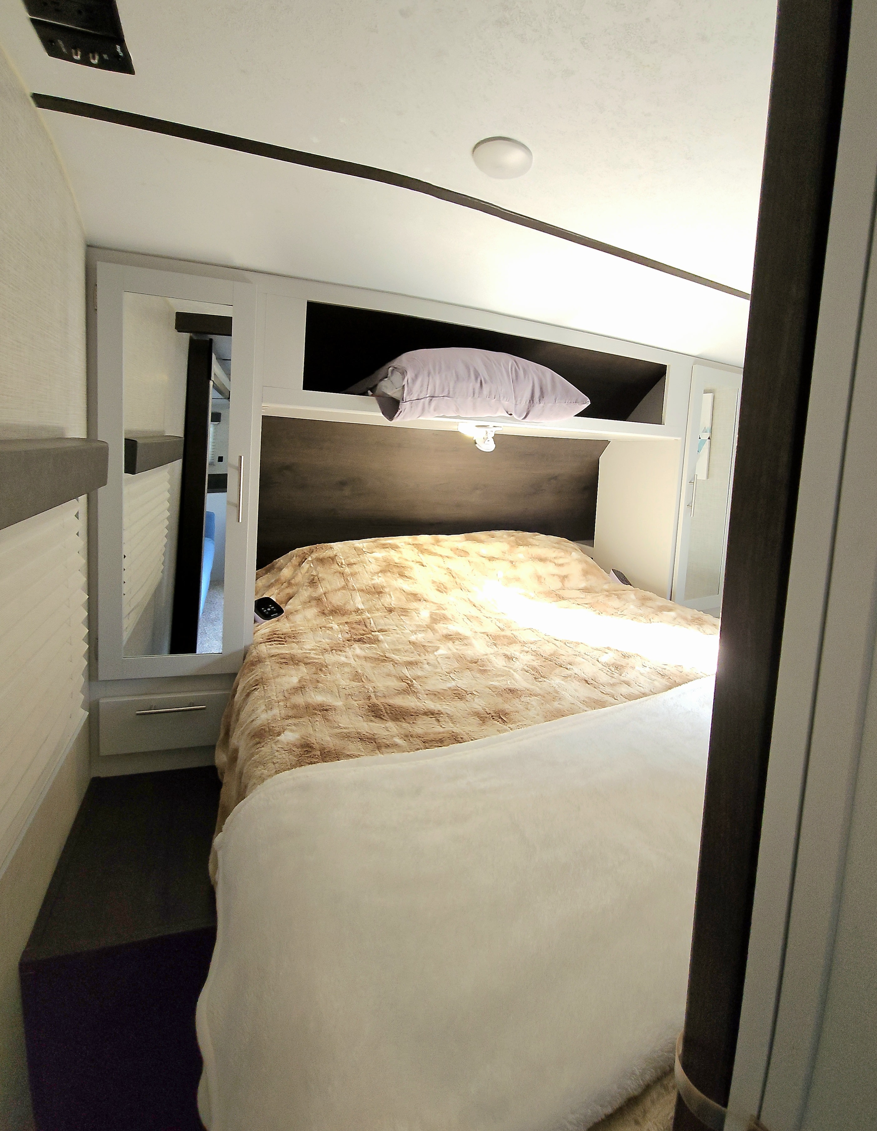 Inside a clean RV rental bedroom featuring a comfy bed, overhead storage, and mirrored wardrobe.. Keystone RV Bullet Ultra Lite 2020