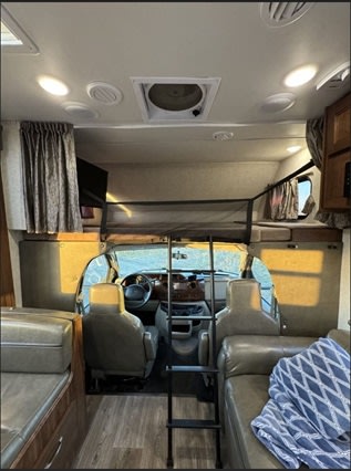 Spacious RV rental interior shows driver's cab, front bunk with ladder, and living area seating. Comfortable travel.. Forest River 3051S Ford 2017
