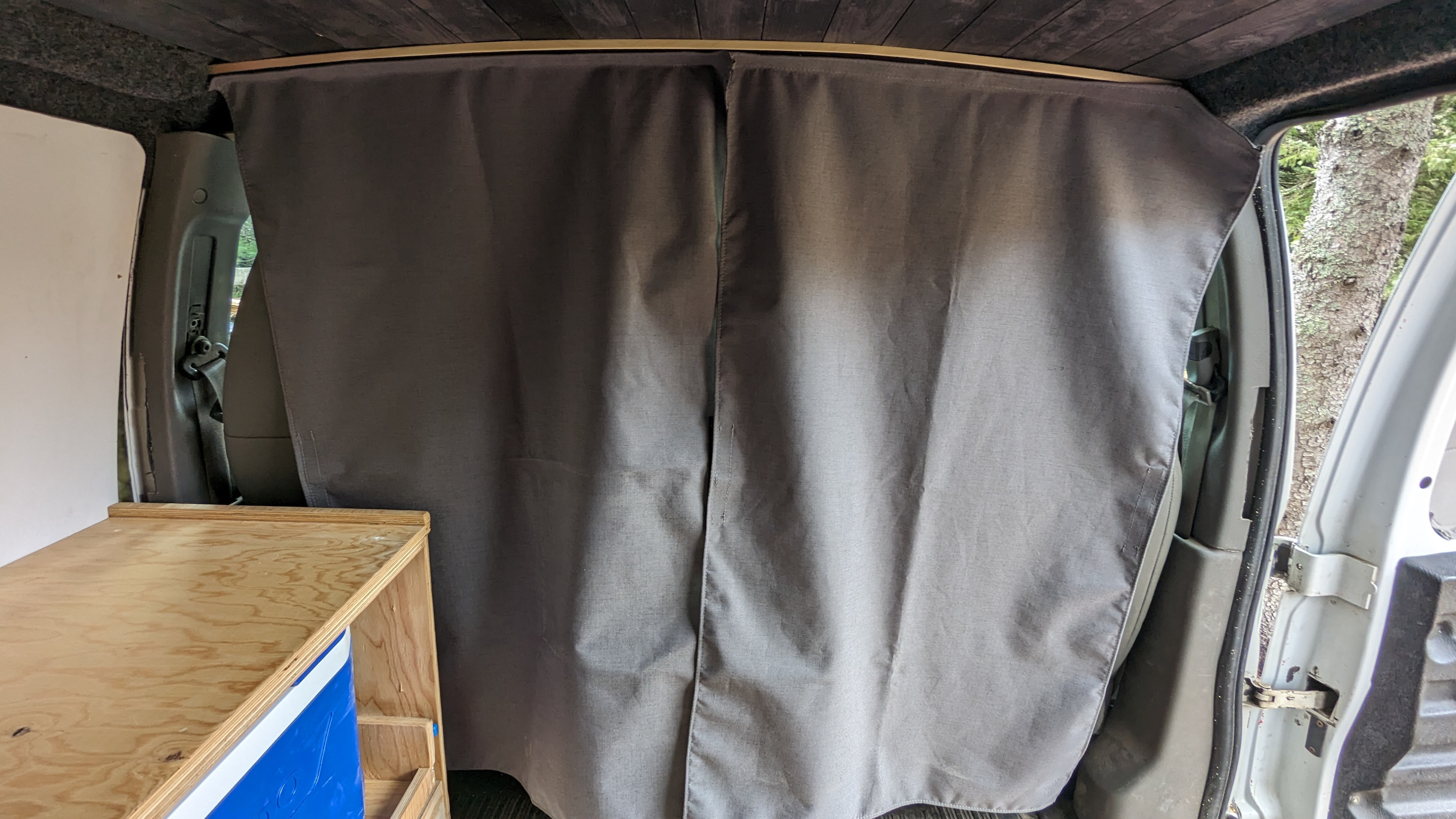 RV rental camper van interior: Grey privacy curtain separates the cab from the custom-built living area with wood ceiling.. Chevrolet Express 2009