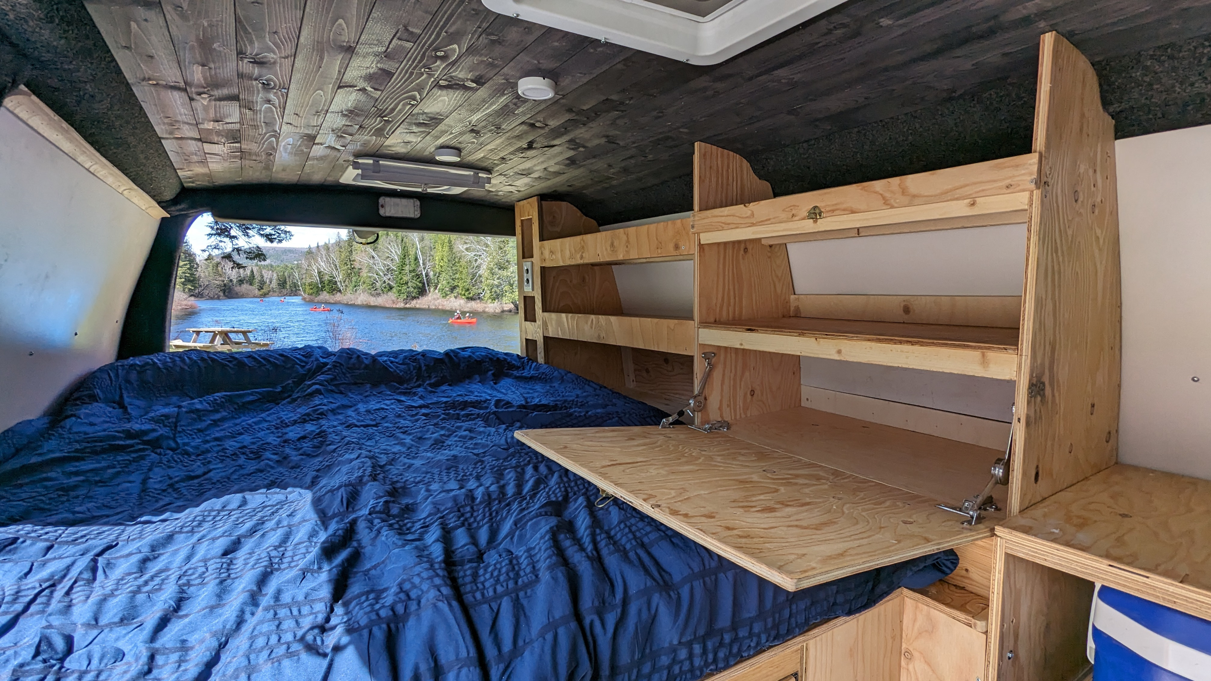 Cozy rv rental camper van with a bed, wood interior & a stunning view of a lake with kayakers and a picnic table.. Chevrolet Express 2009