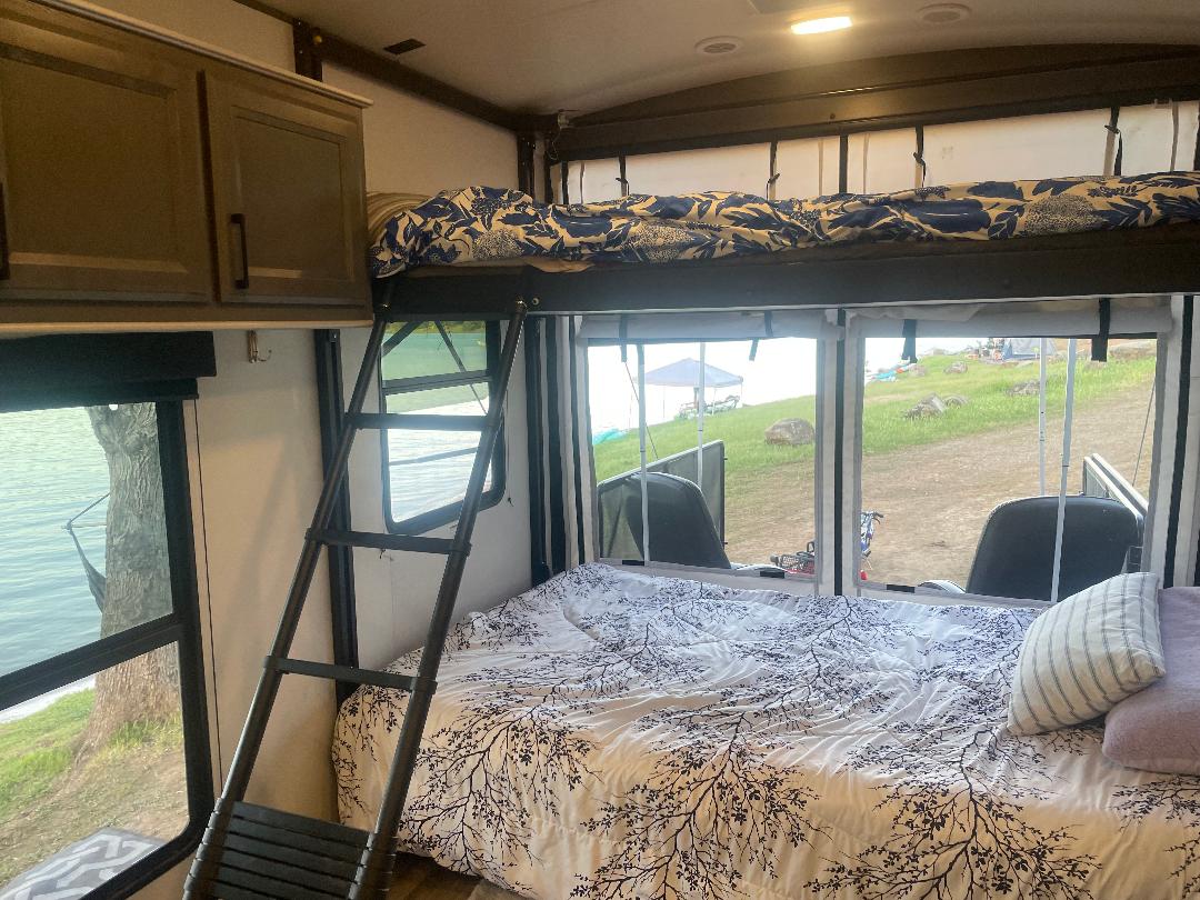 Cozy RV rental interior with bunk beds, overlooking a serene lake. Perfect for your next glamping adventure!. Heartland 265 2021