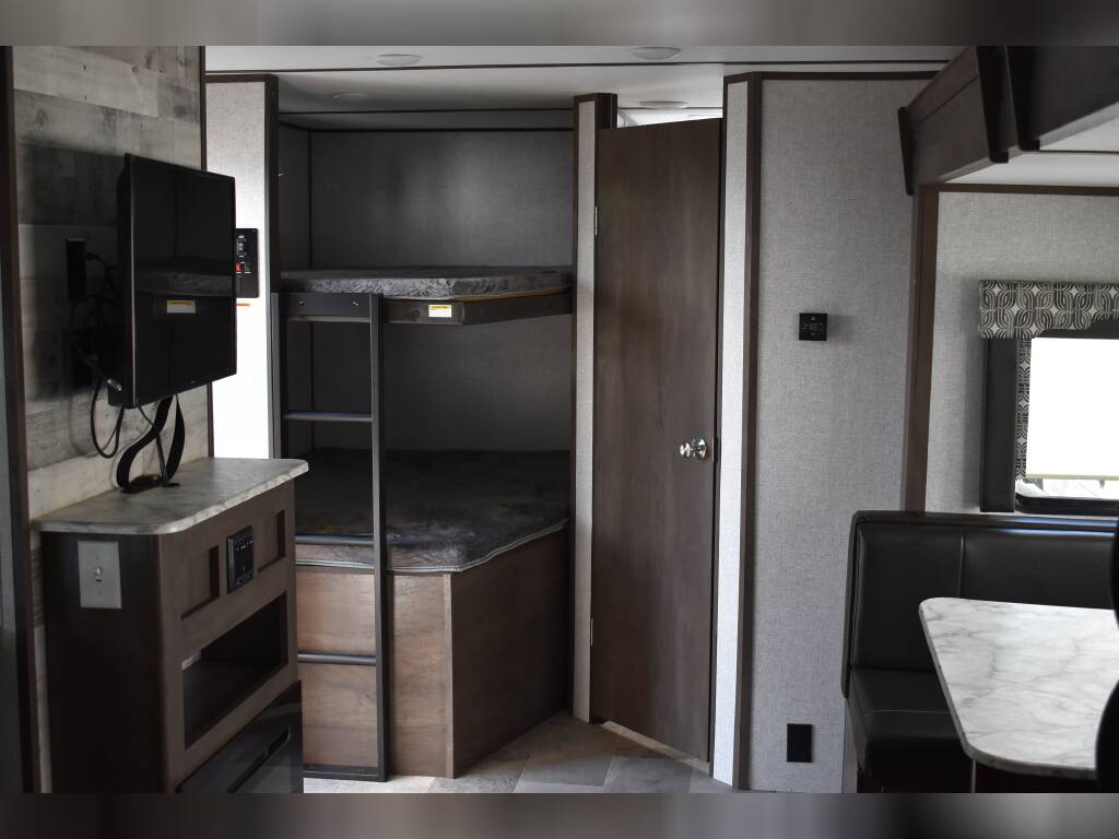 RV rental interior featuring bunk beds, TV, and dining area, ideal for family travel.. Dutchmen Coleman Light 2021