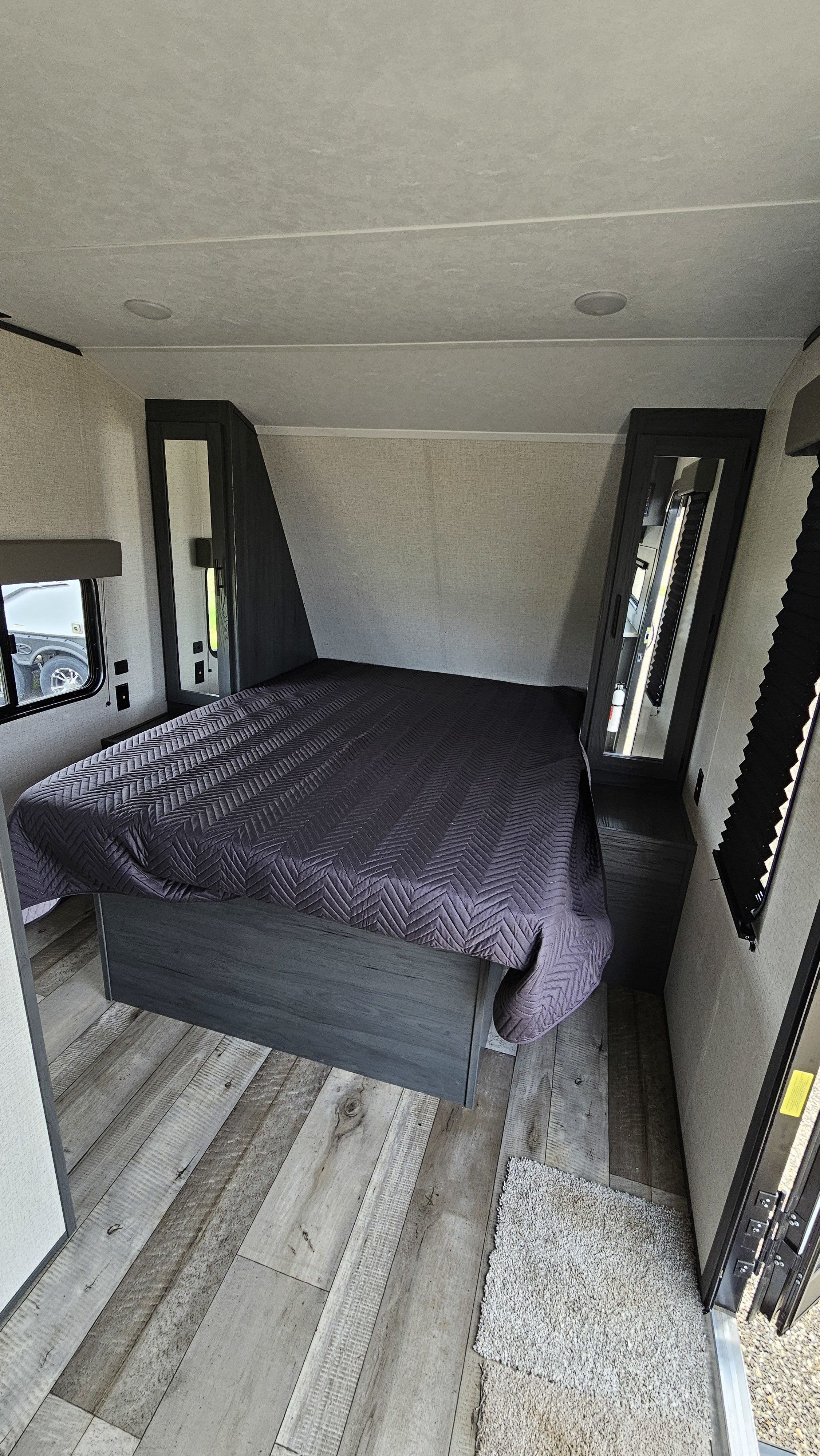 Cozy RV rental bedroom featuring a dark bed, light wood-look floor, and built-in storage. Perfect for travel comfort.. Aspen Trail LE 2022