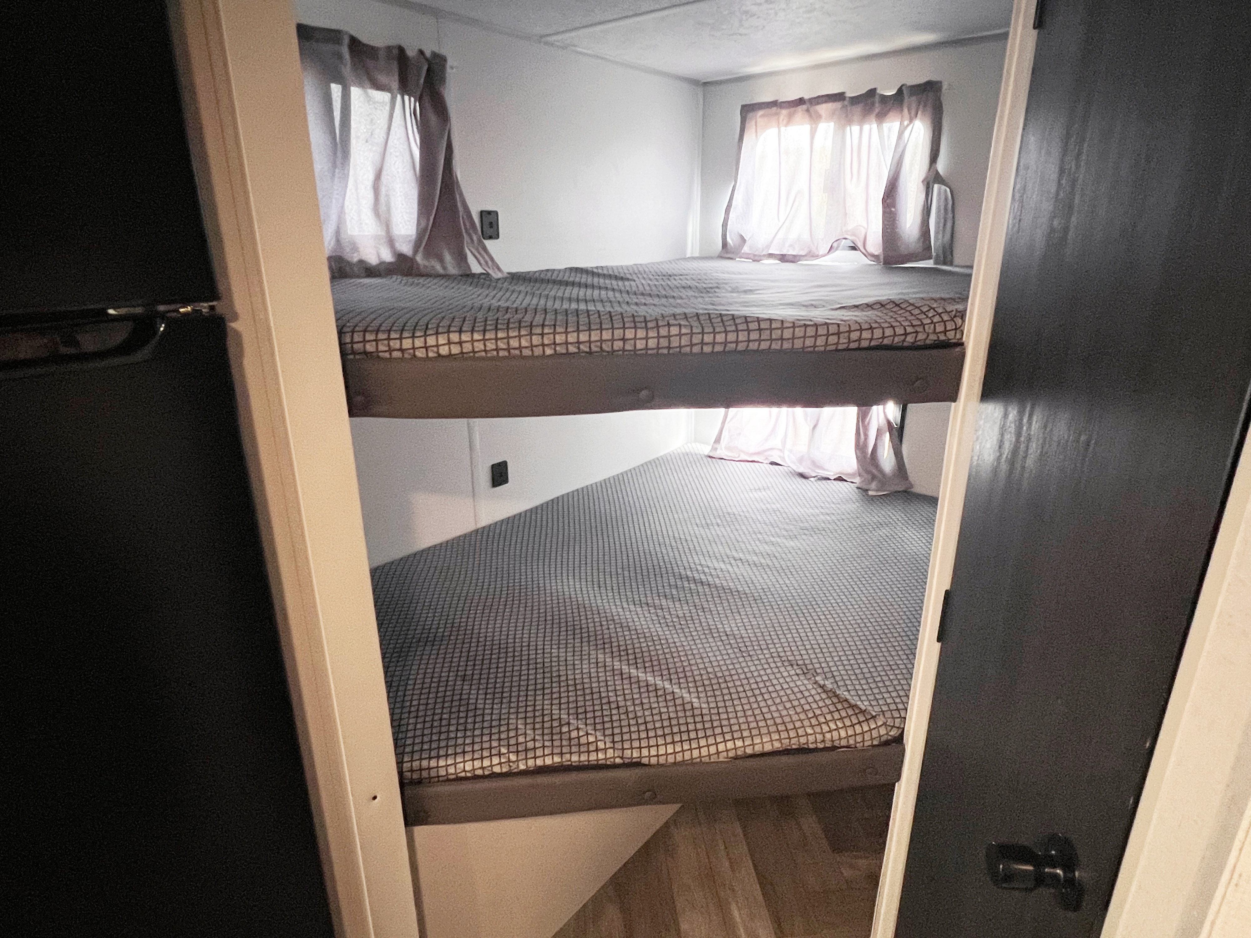 Cozy RV rental interior featuring spacious bunk beds with patterned mattresses and windows, ideal for compact travel.. Wildwood FSX 2021