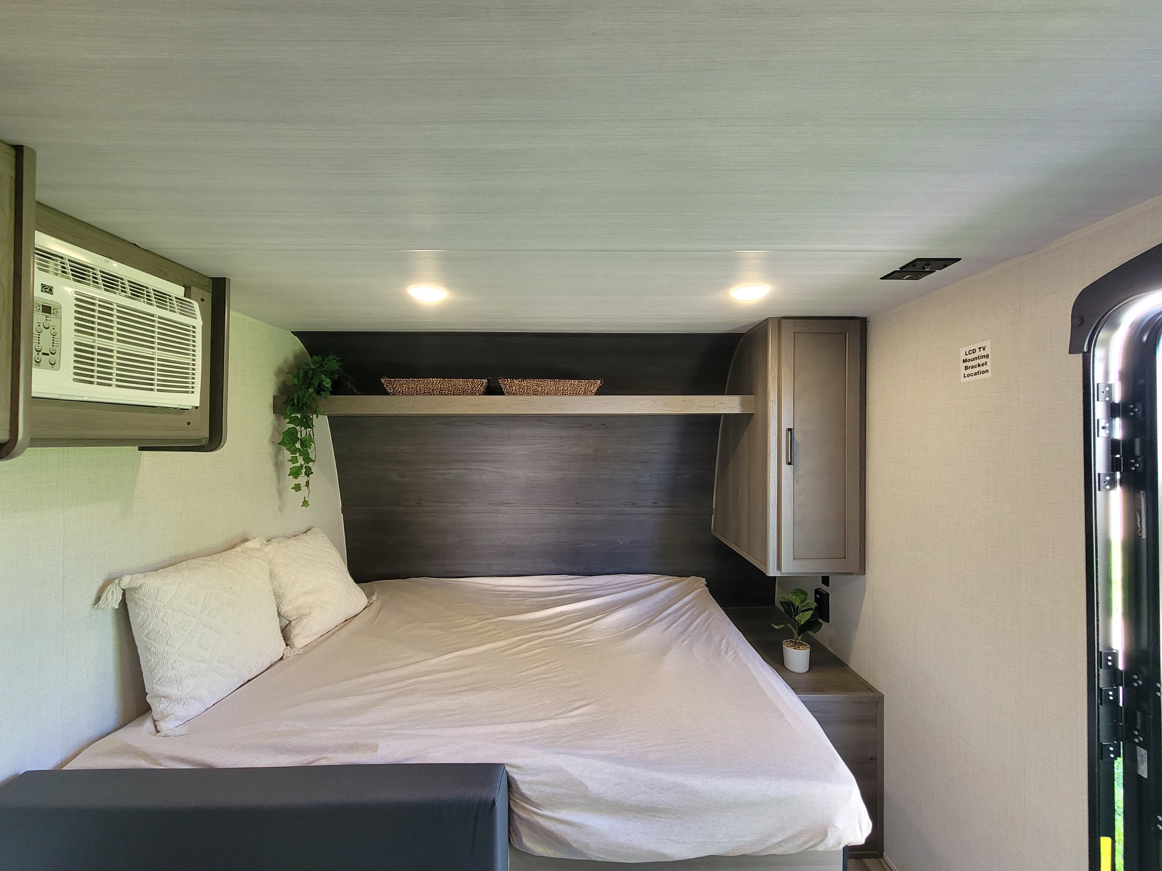 Bright & cozy RV rental sleeping area with a comfortable bed, AC, and convenient overhead storage.. Keystone RV Hideout 2024