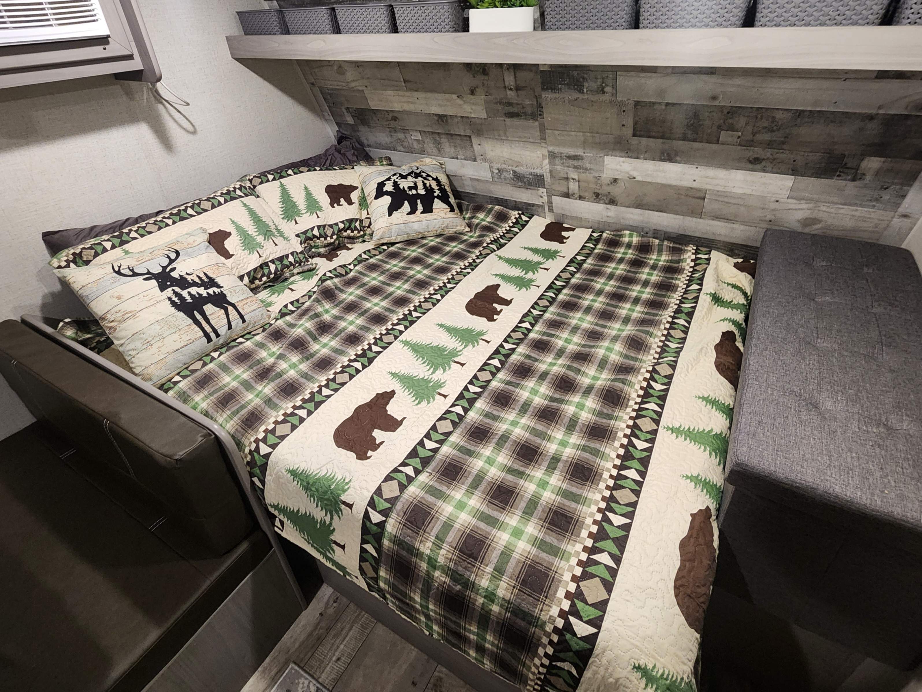 Cozy RV rental bedroom with rustic plaid and nature-themed bedding. Features bear, deer, & tree designs for a comfy stay.. Other 17B 2023