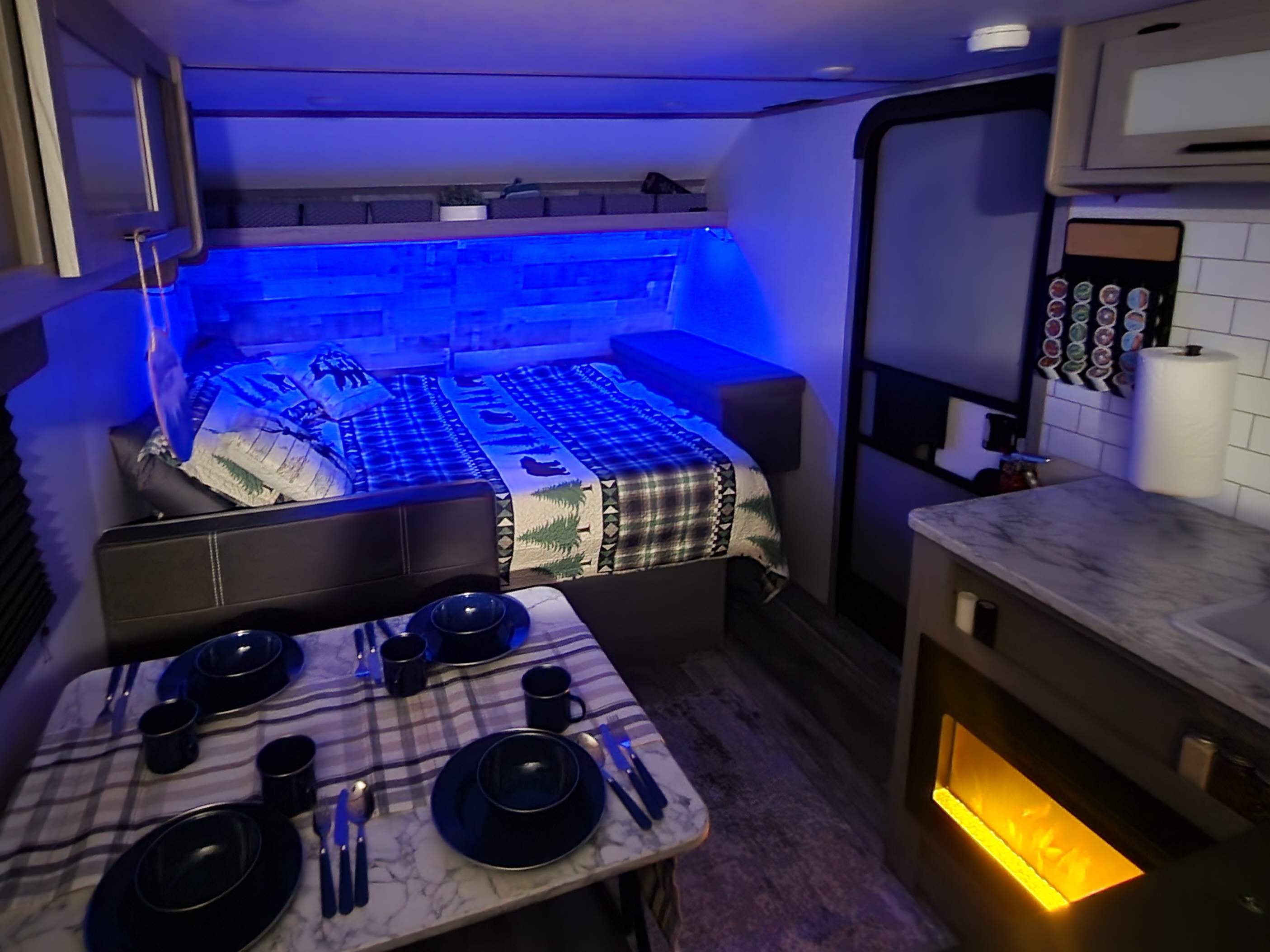 Cozy RV rental interior with bed, dining area, and kitchen, featuring atmospheric blue lighting for a comfortable stay.. Other 17B 2023
