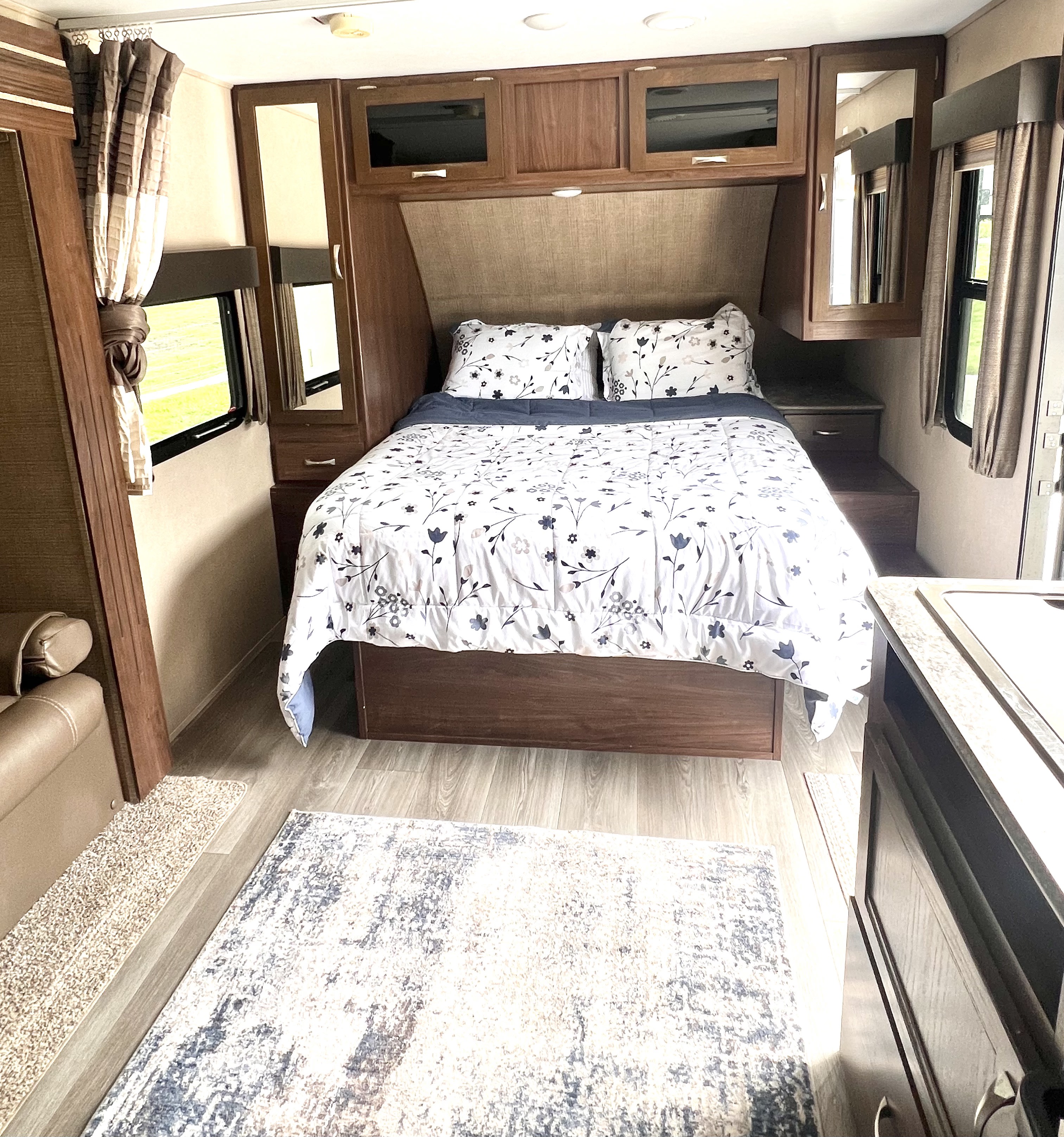 Cozy RV rental bedroom featuring floral bedding, overhead storage, and wood-look flooring, offering comfort on the go.. Dutchmen Coleman Light 2018