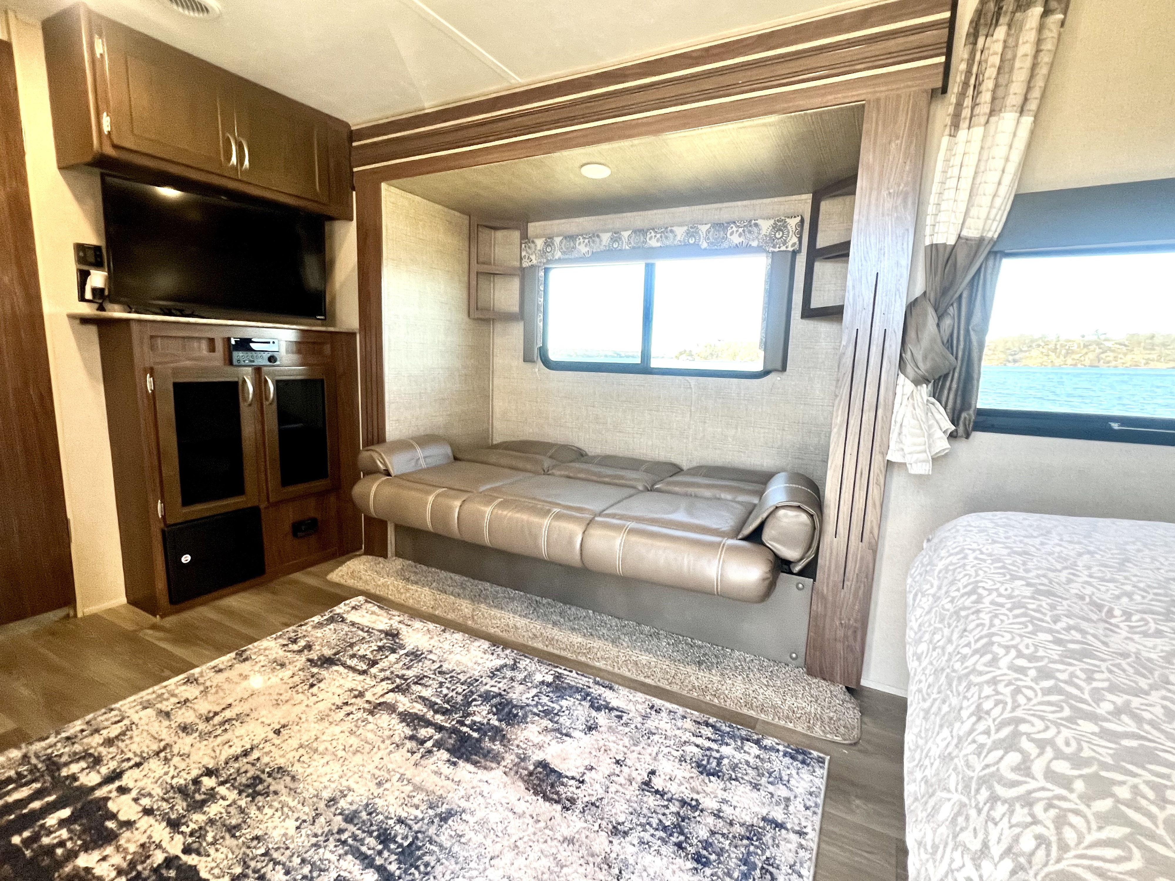 Step inside this RV rental's inviting living space: a light brown sofa, entertainment system, and comfortable bed await.. Dutchmen Coleman Light 2018