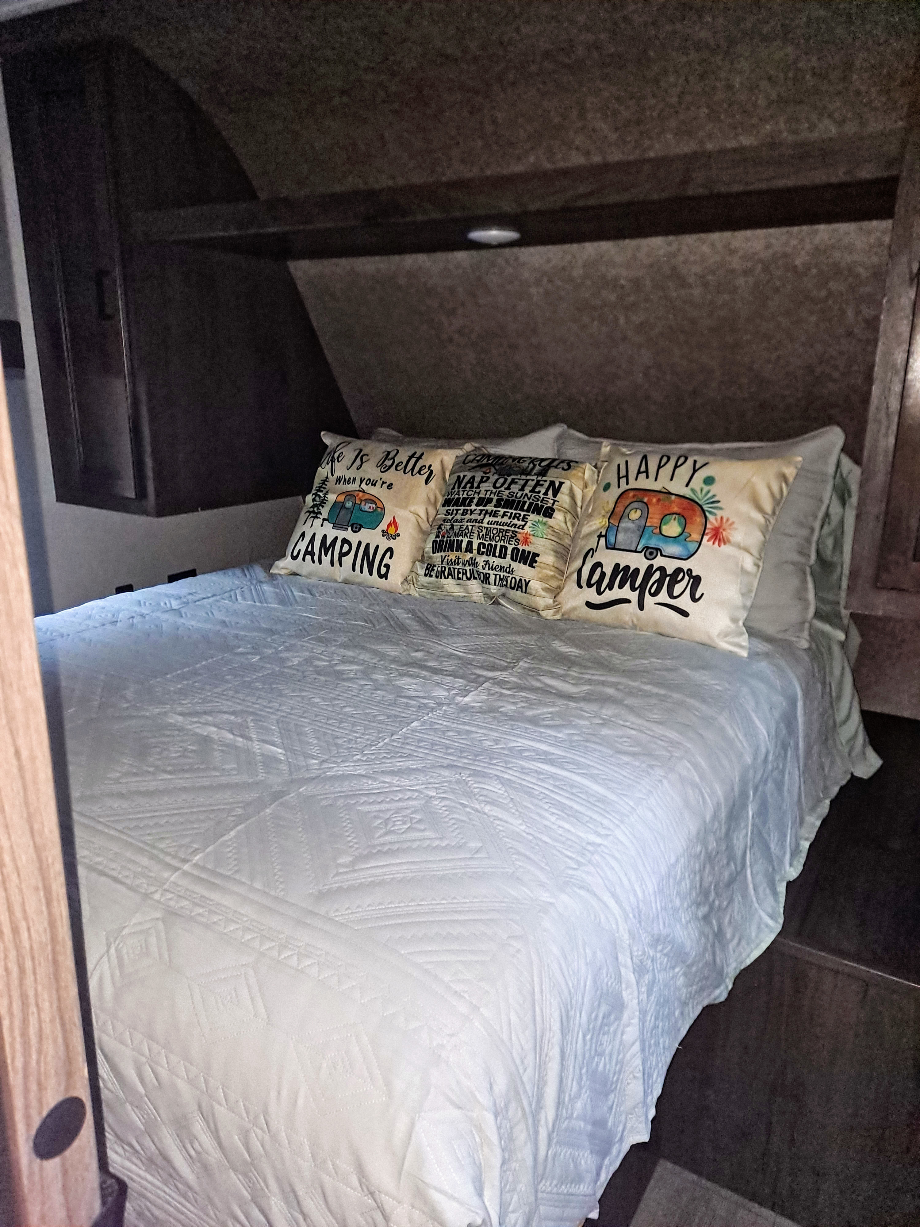 Cozy RV rental bedroom with a comfy bed, white quilt, and fun camping-themed pillows. Perfect for your next adventure!. Highland Ridge RV Open Range 2021