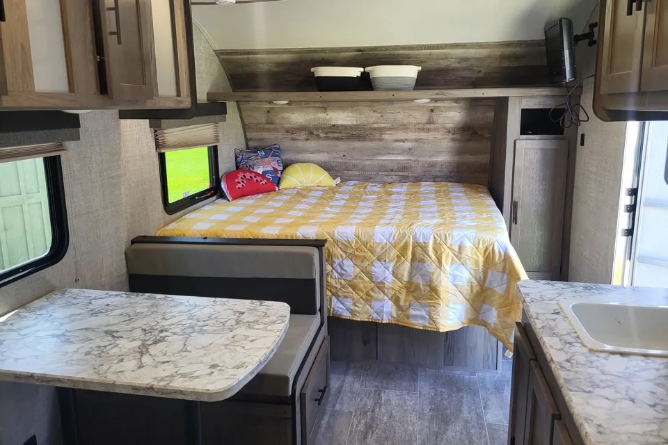 Cozy RV rental interior featuring a comfy bed, dinette, and compact kitchen area with a sink.. Grand River Bunkhouse Ultra-Lite Series 2020
