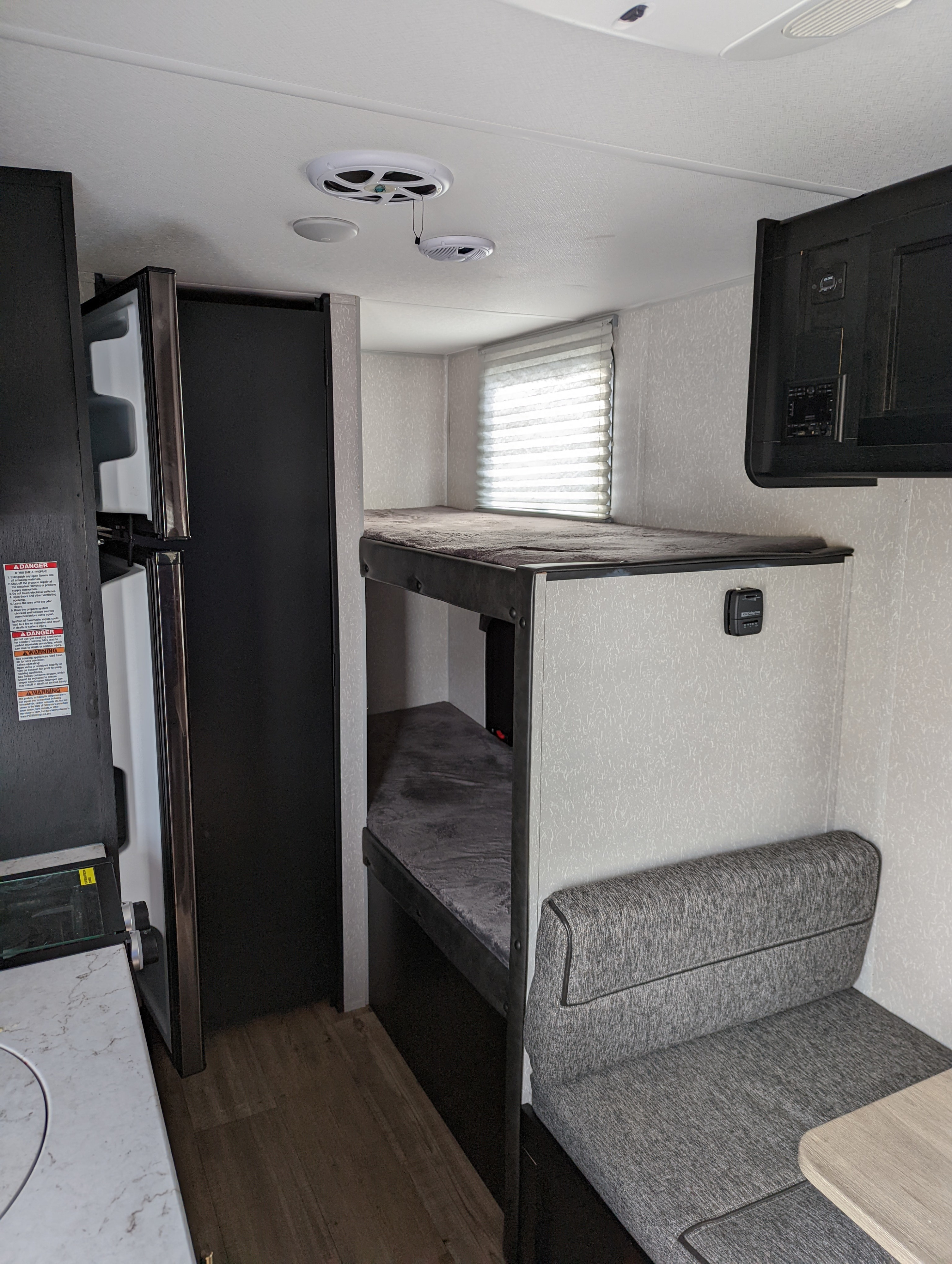 Compact RV rental interior featuring bunk beds, a kitchen area, and comfortable seating, ideal for travel.. Forest River Cherokee Wolf Pup 2022