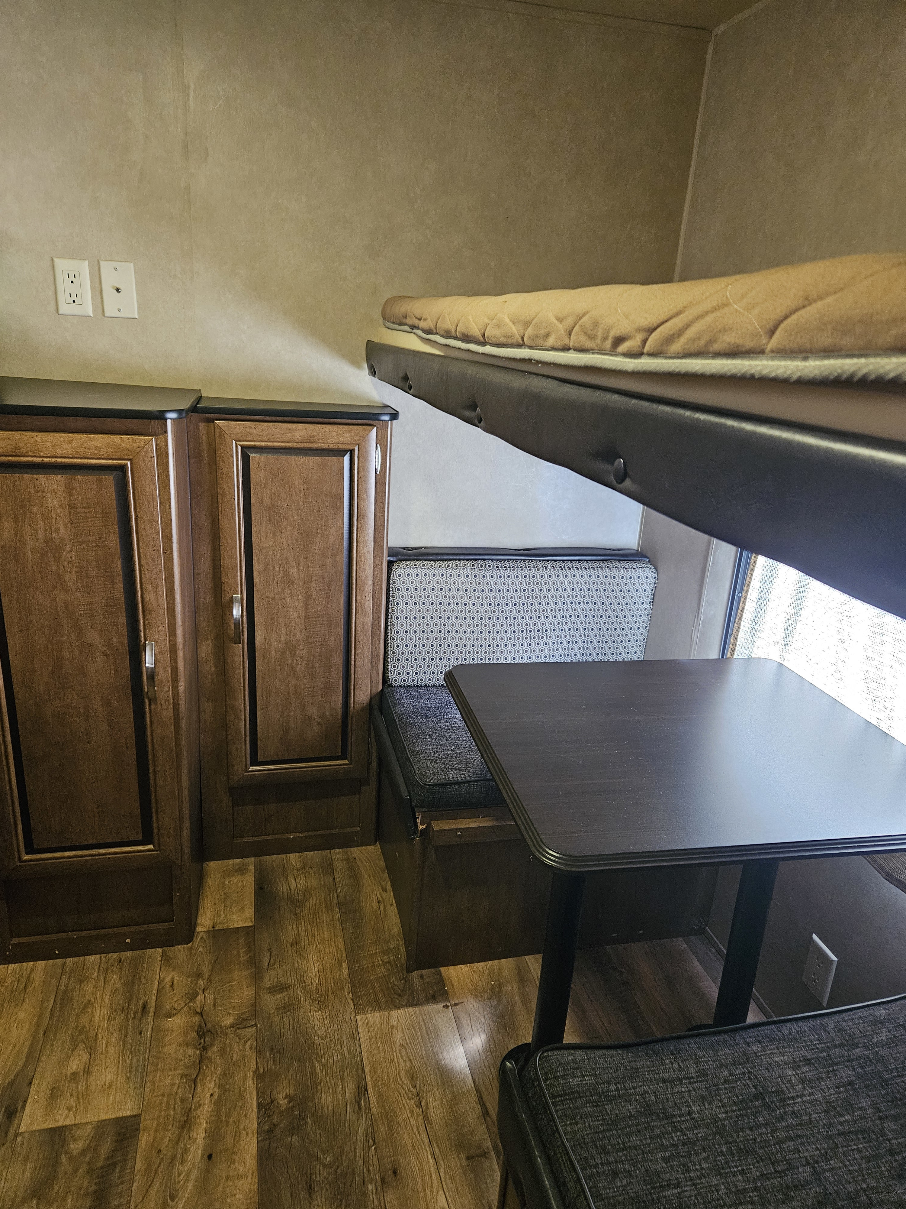 RV rental interior: a bunk bed above a dinette, with dark wood cabinets and laminate flooring.. Forest River Salem 2017