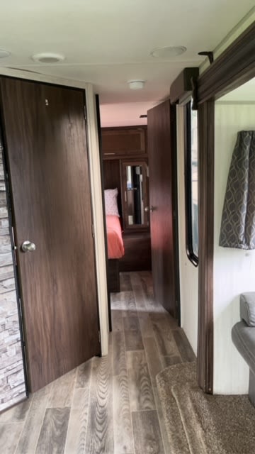 RV rental: Modern hallway with wood-look flooring leads to a cozy bedroom. A gray sofa is visible on the right.. Forest River Cherokee 2019