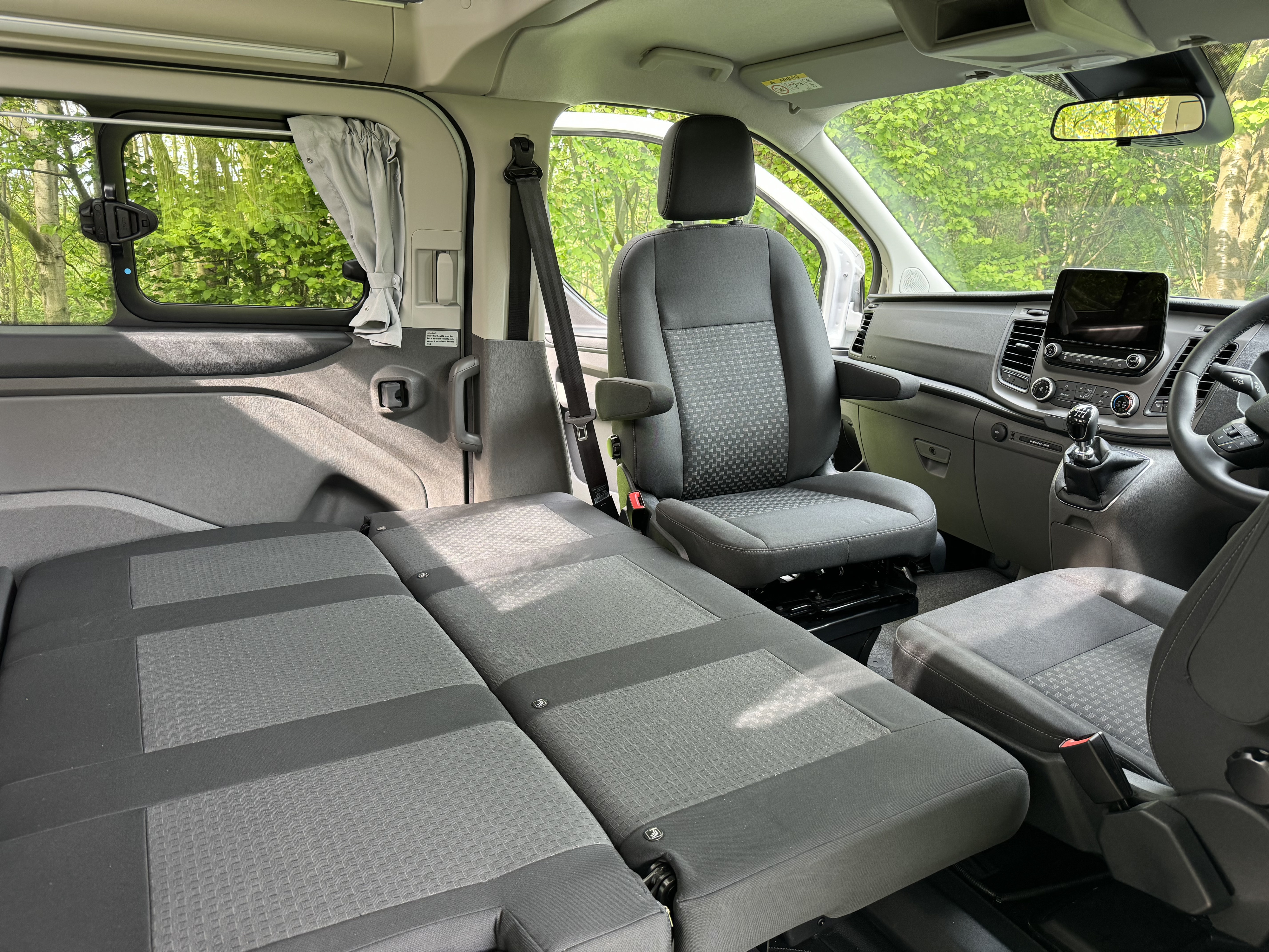 RV rental camper van interior: rear seats convert to a bed, front seat swivels for flexible living and sleeping.. Ford Nugget 2022