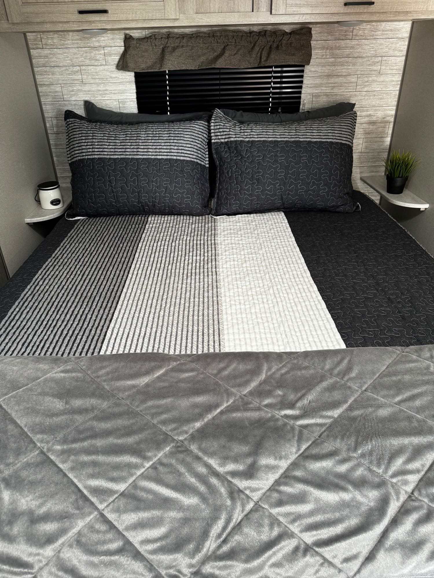 Experience comfort in this RV rental! The cozy bed features stylish striped bedding and soft quilted accents, perfect for relaxing trips.. Forest River Aurora 2024