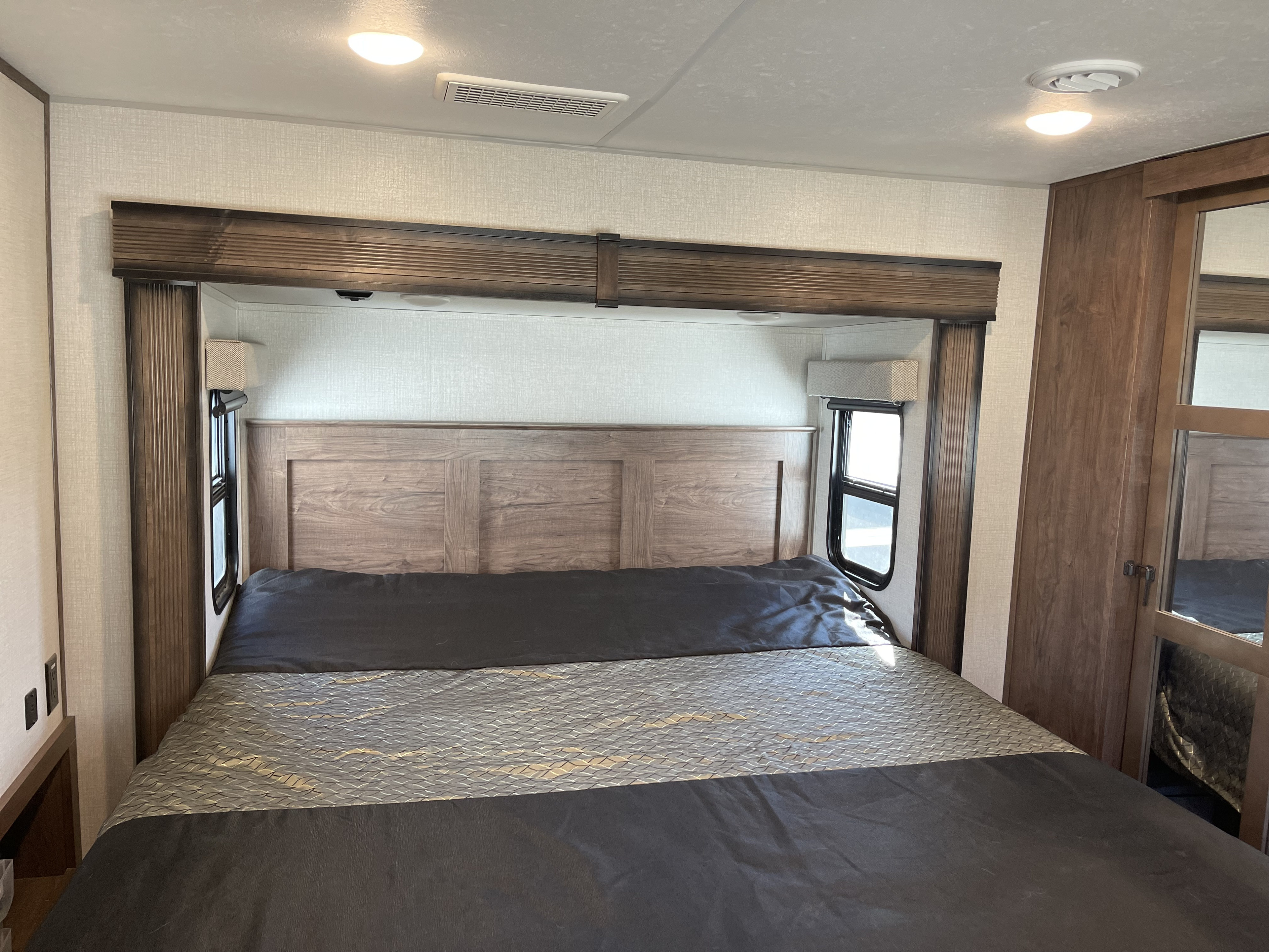 Step inside a modern RV rental bedroom featuring a spacious bed, wooden headboard, and built-in storage. Perfect for road trips.. KZ Recreational Vehicles Durango Gold 2021