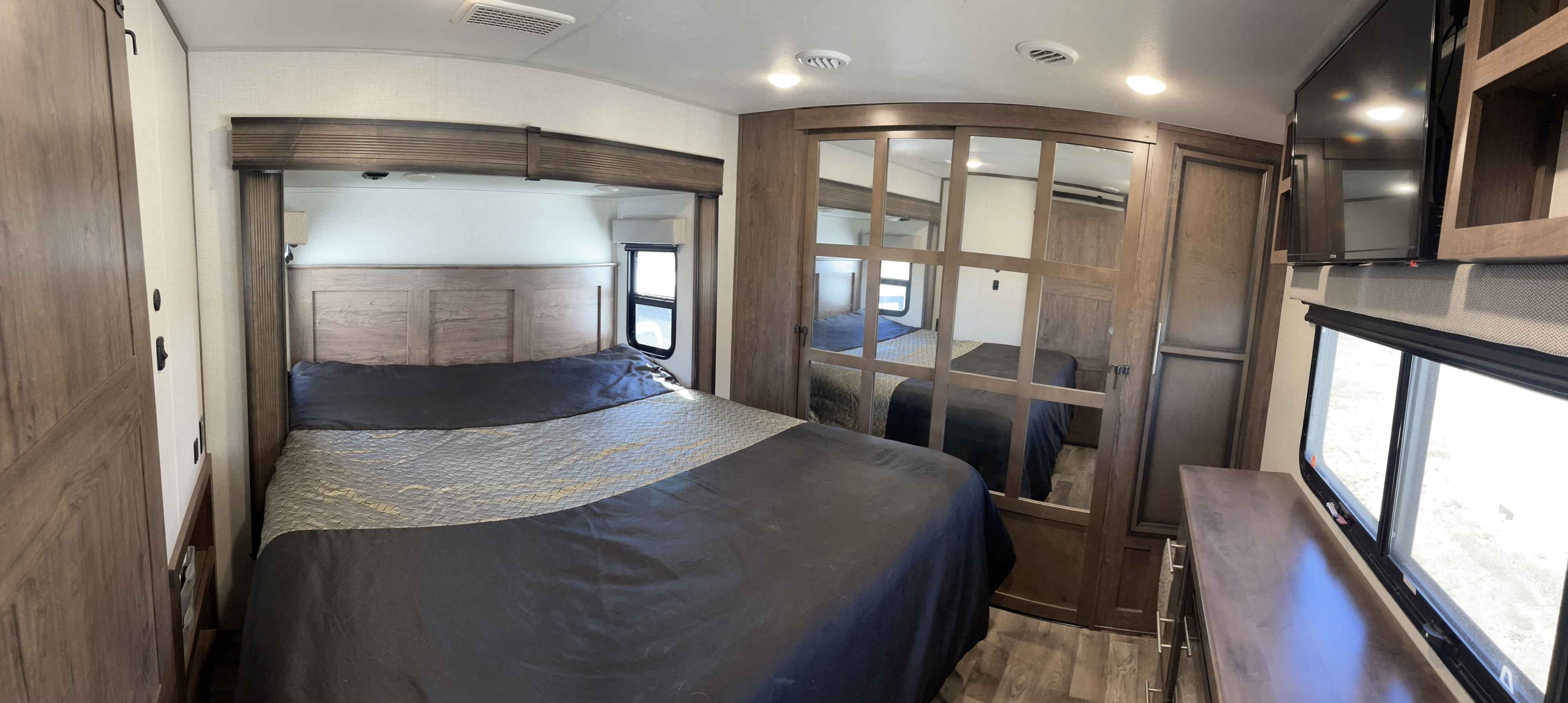 Experience comfort in an **rv rental**! This modern bedroom offers a large bed, mirrored closet, and wall-mounted TV.. KZ Recreational Vehicles Durango Gold 2021