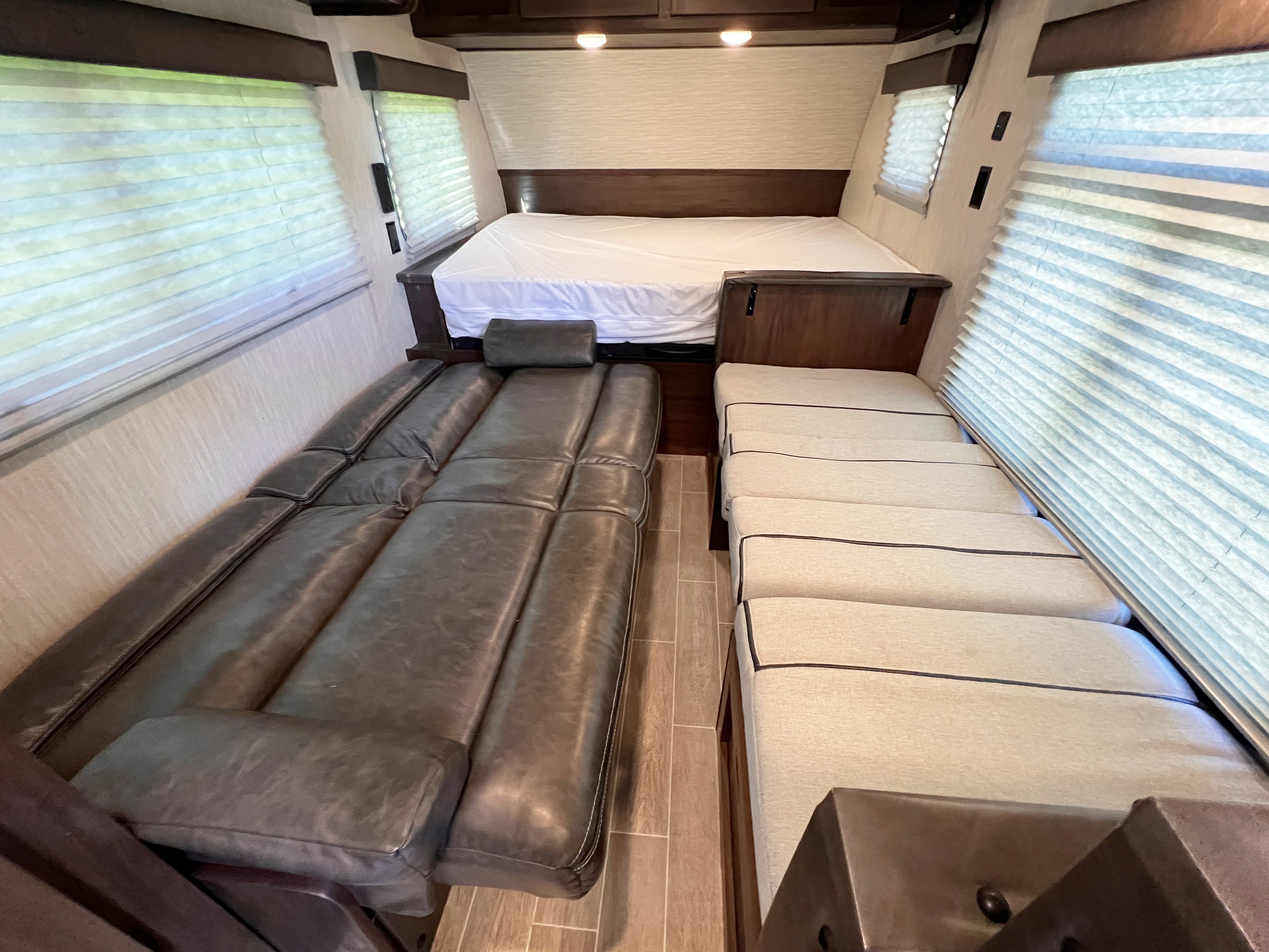 RV rental interior: A compact living space featuring a rear bed, a long left sofa, and a right bench seat with blinds.. Forest River Cherokee Wolf Pup 2021