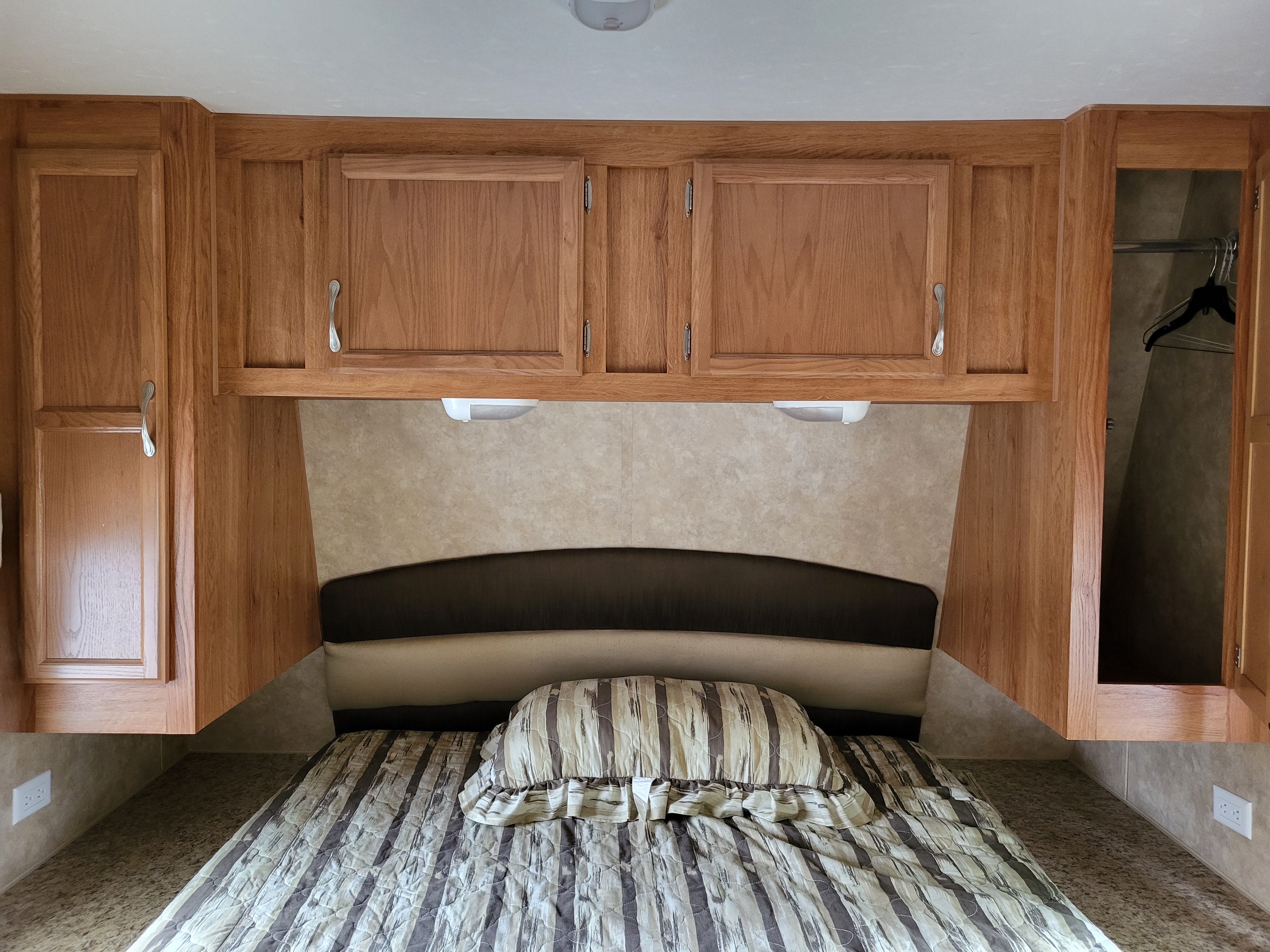 Cozy RV rental bedroom with wooden cabinets, overhead lights, and a wardrobe. Perfect for your next adventure.. Jayco Jay Flight 2008