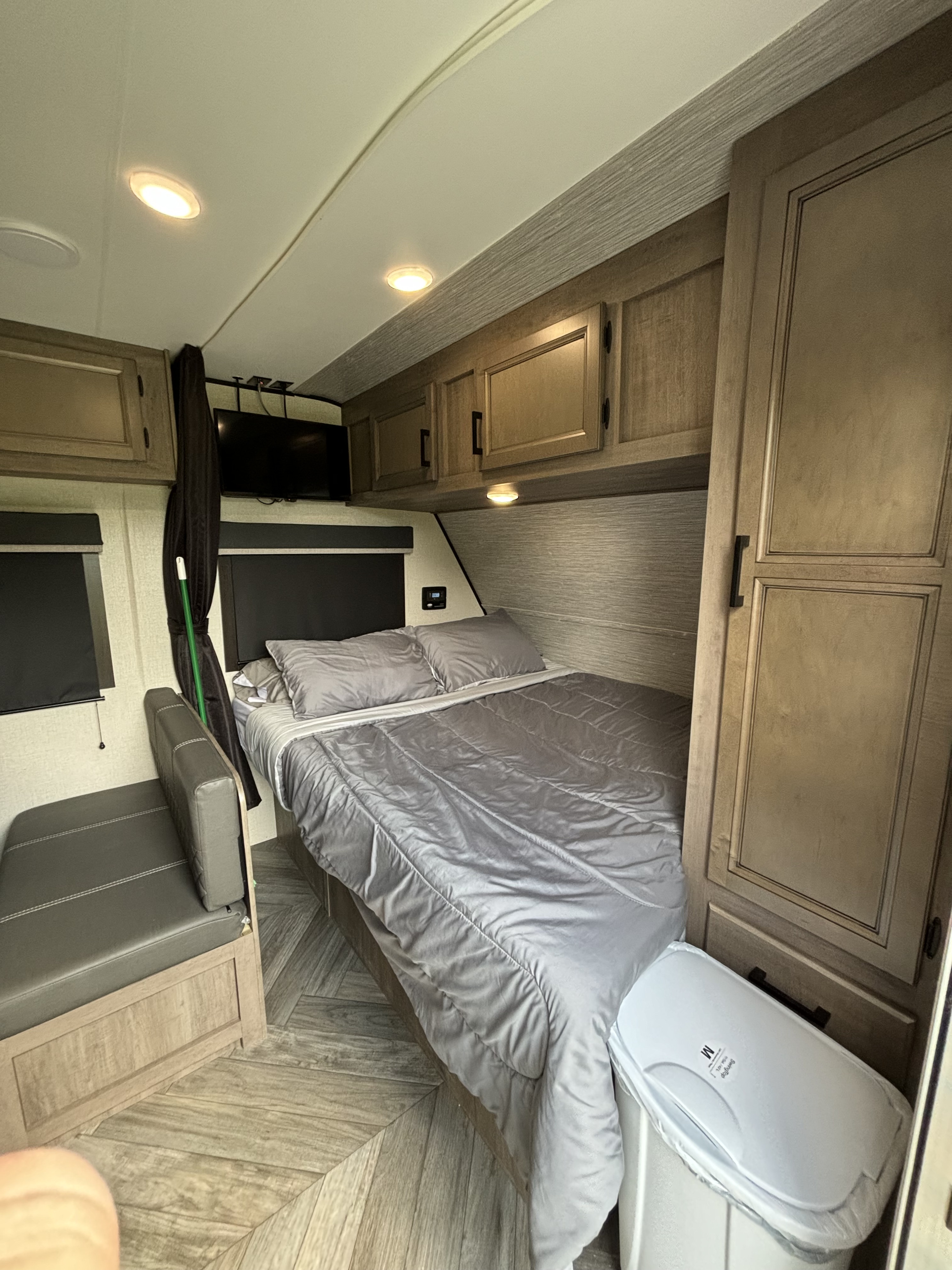 This functional RV rental bedroom features a comfortable bed, convenient seating, TV, and practical overhead cabinets.. Olympia Sport 19BH 2022