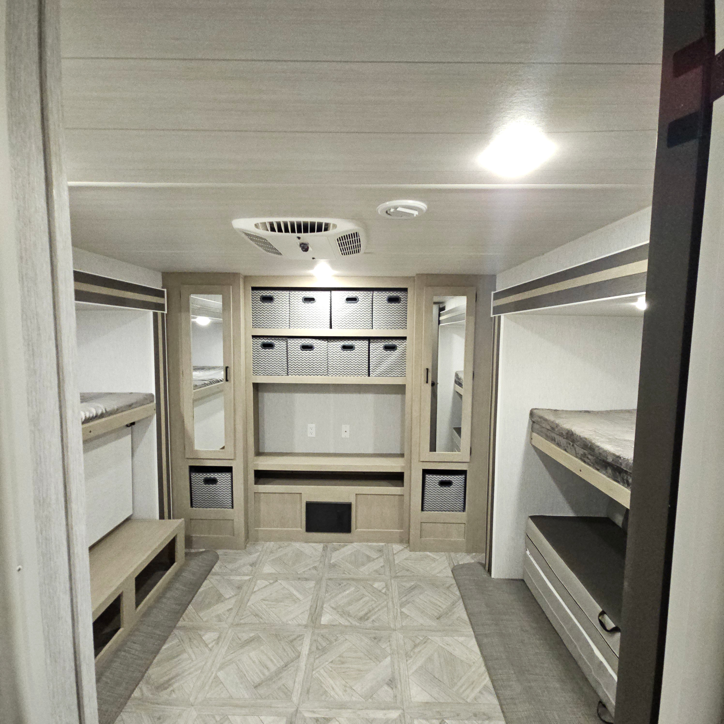Spacious RV rental interior featuring comfortable bunk beds, a central entertainment area, and ample storage baskets.. Forest River Salem Platinum 2023