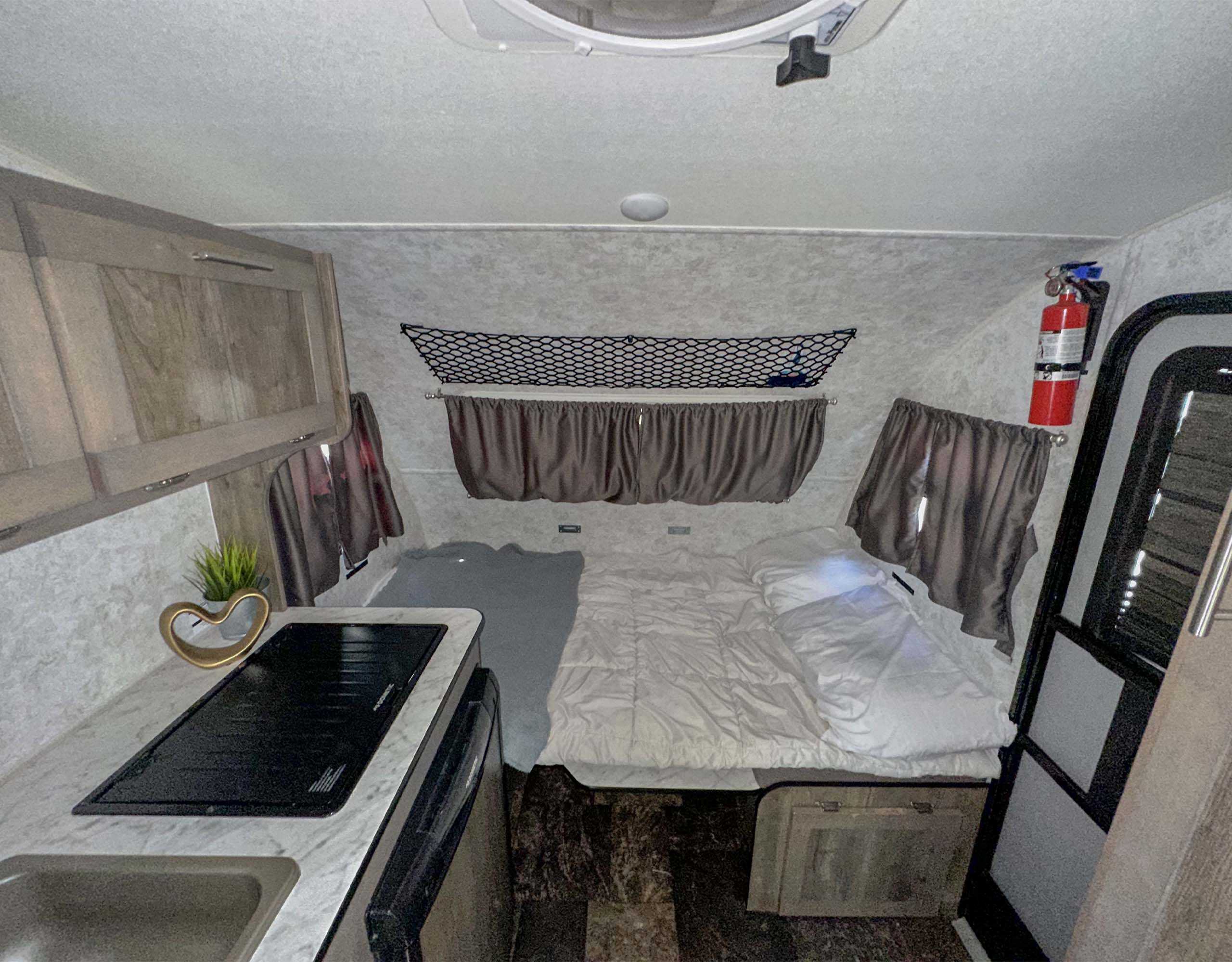 Cozy RV rental interior with kitchen, bed, and practical storage solutions for your travels.. Prolite Mini 2022