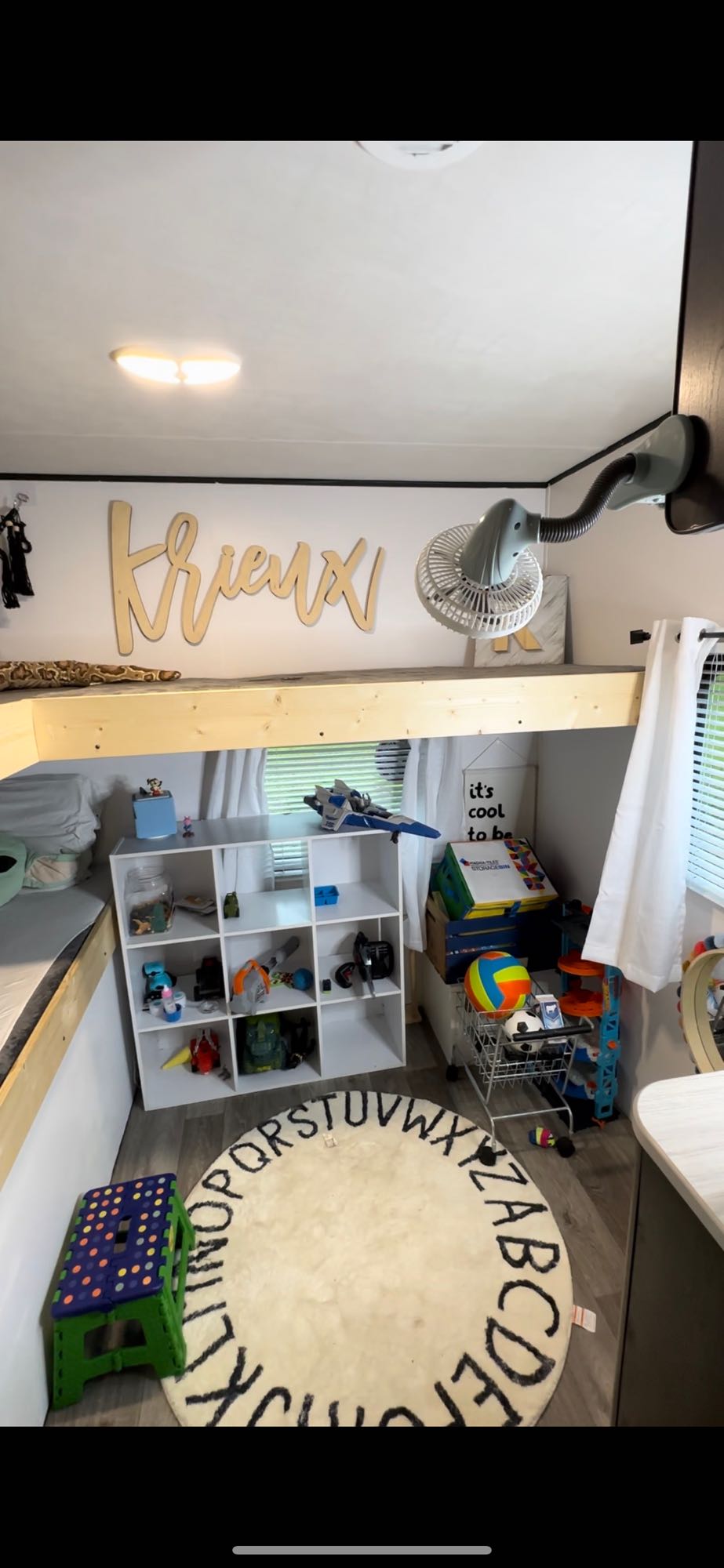 This cozy kids' space in an RV rental features a bunk bed, toy storage, alphabet rug, and fan. Perfect for travel!. Heartland RVs Pioneer 2021