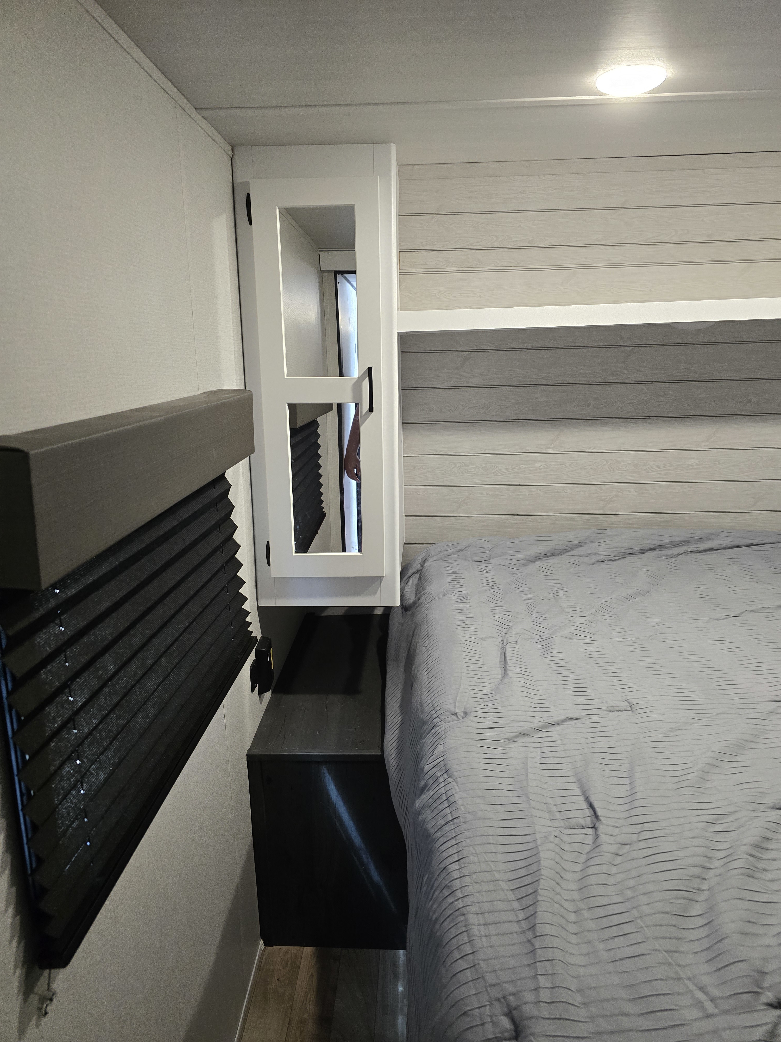 RV rental bedroom showcasing a comfortable gray bed, built-in storage cabinet, and window blinds for a cozy travel space.. Keystone RV Hideout 2023